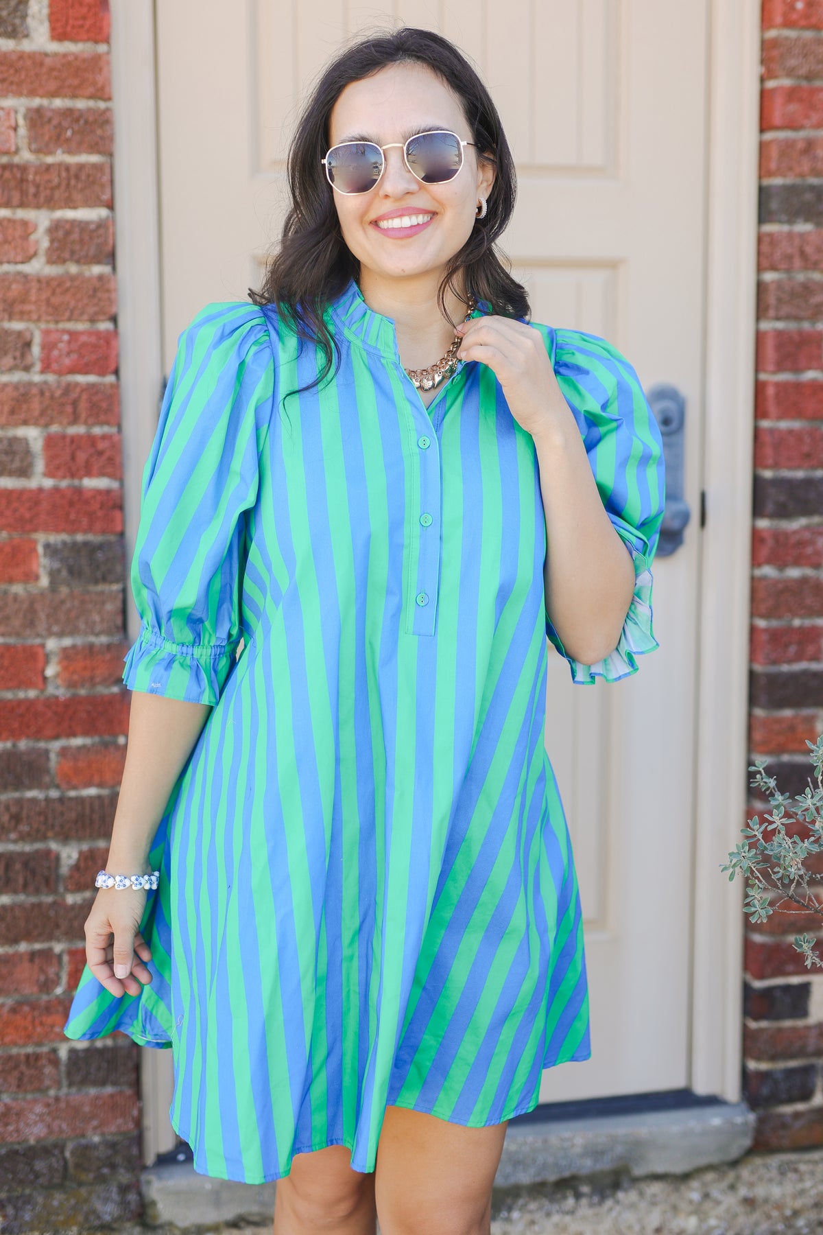 Woman wearing a green and blue striped dress outside with sunglasses.