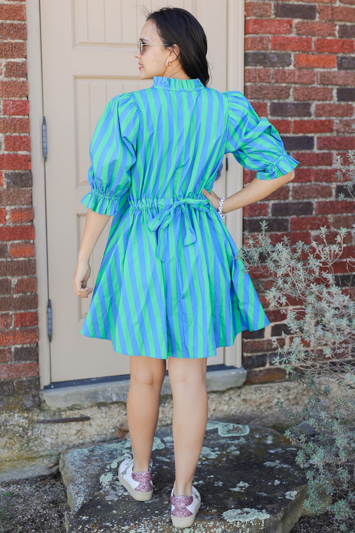Woman wearing a green and blue striped dress outside with sunglasses.