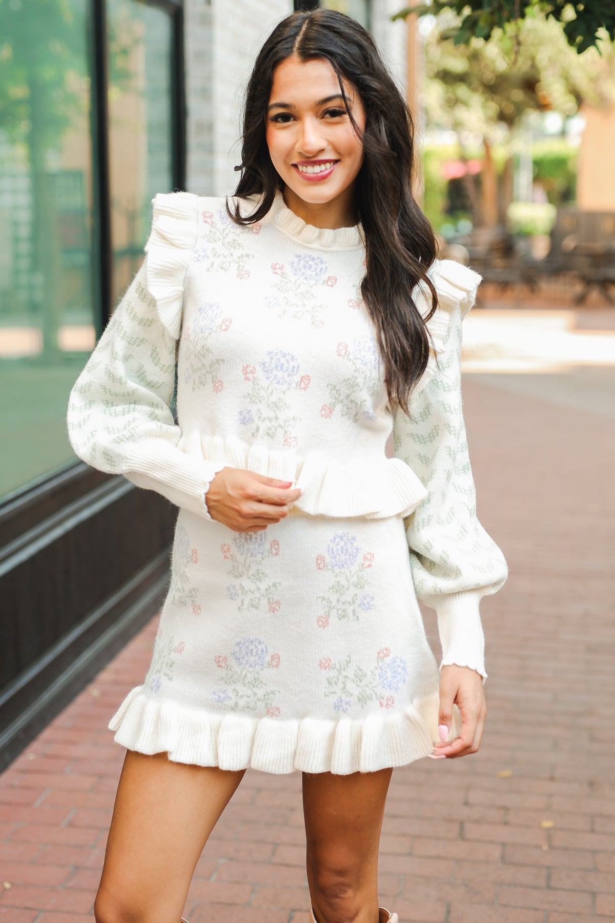 Woman wearing a white floral dress standing outdoors.