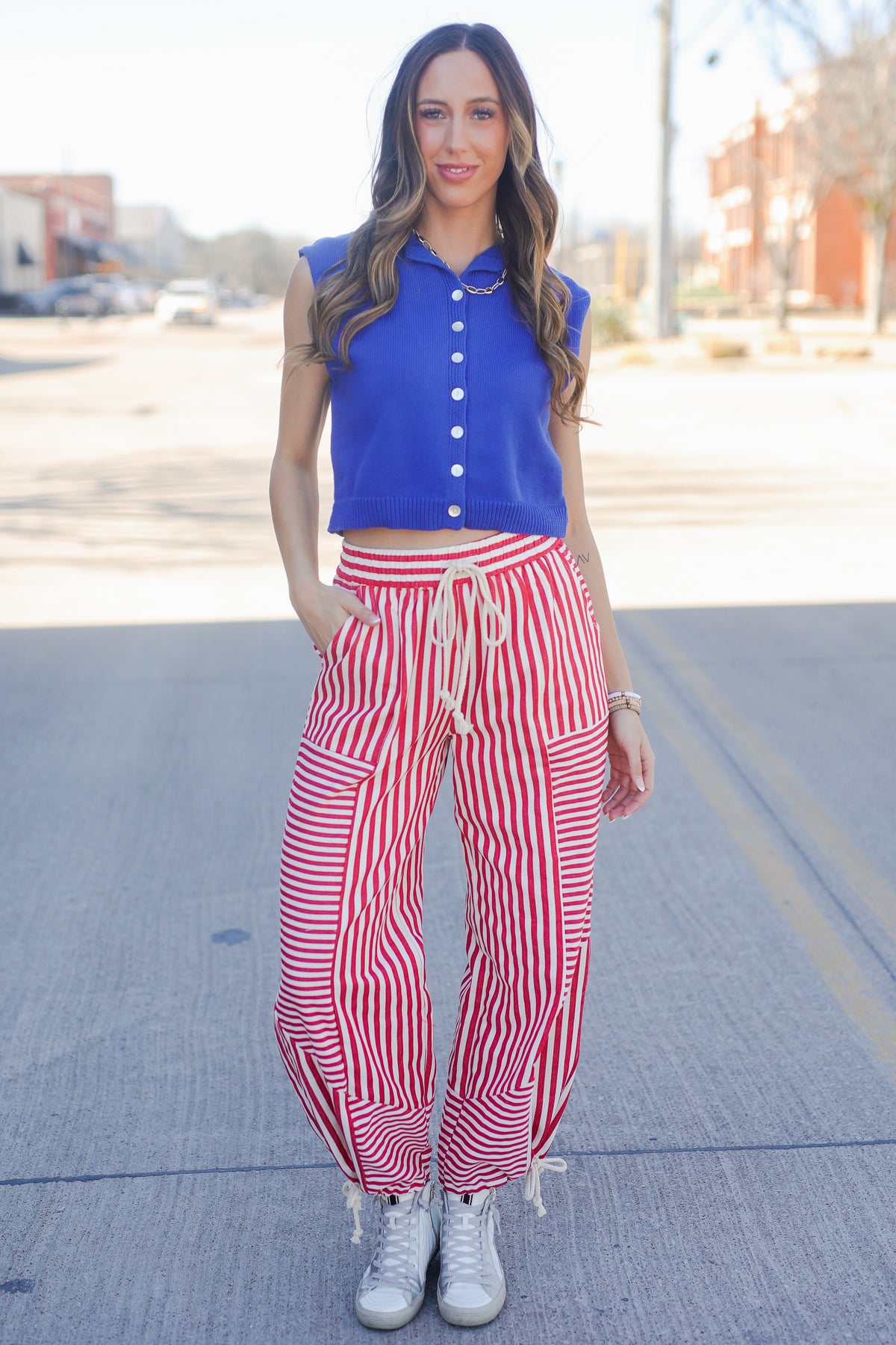 Woman wearing a blue top and red striped pants on a street.
