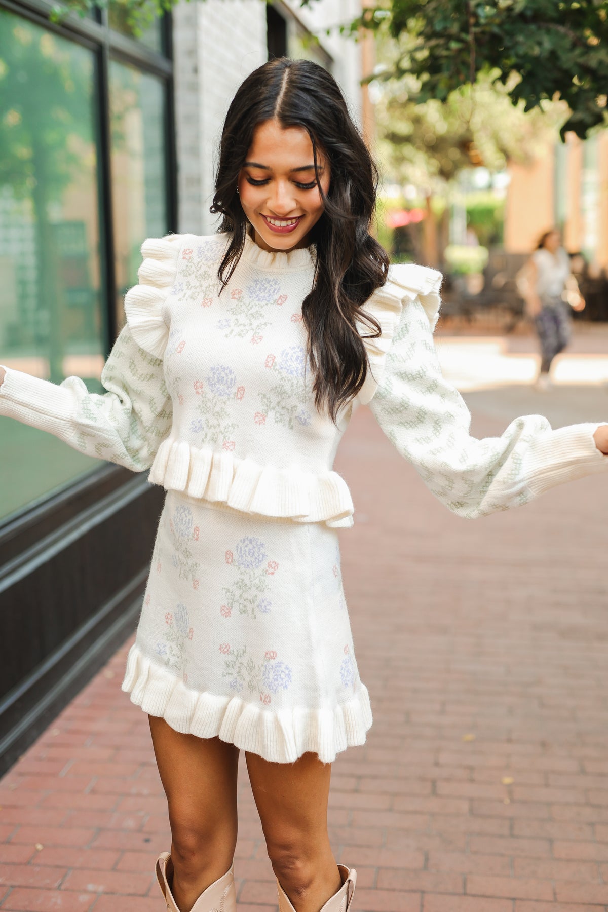 Woman in a white floral dress standing on a sidewalk