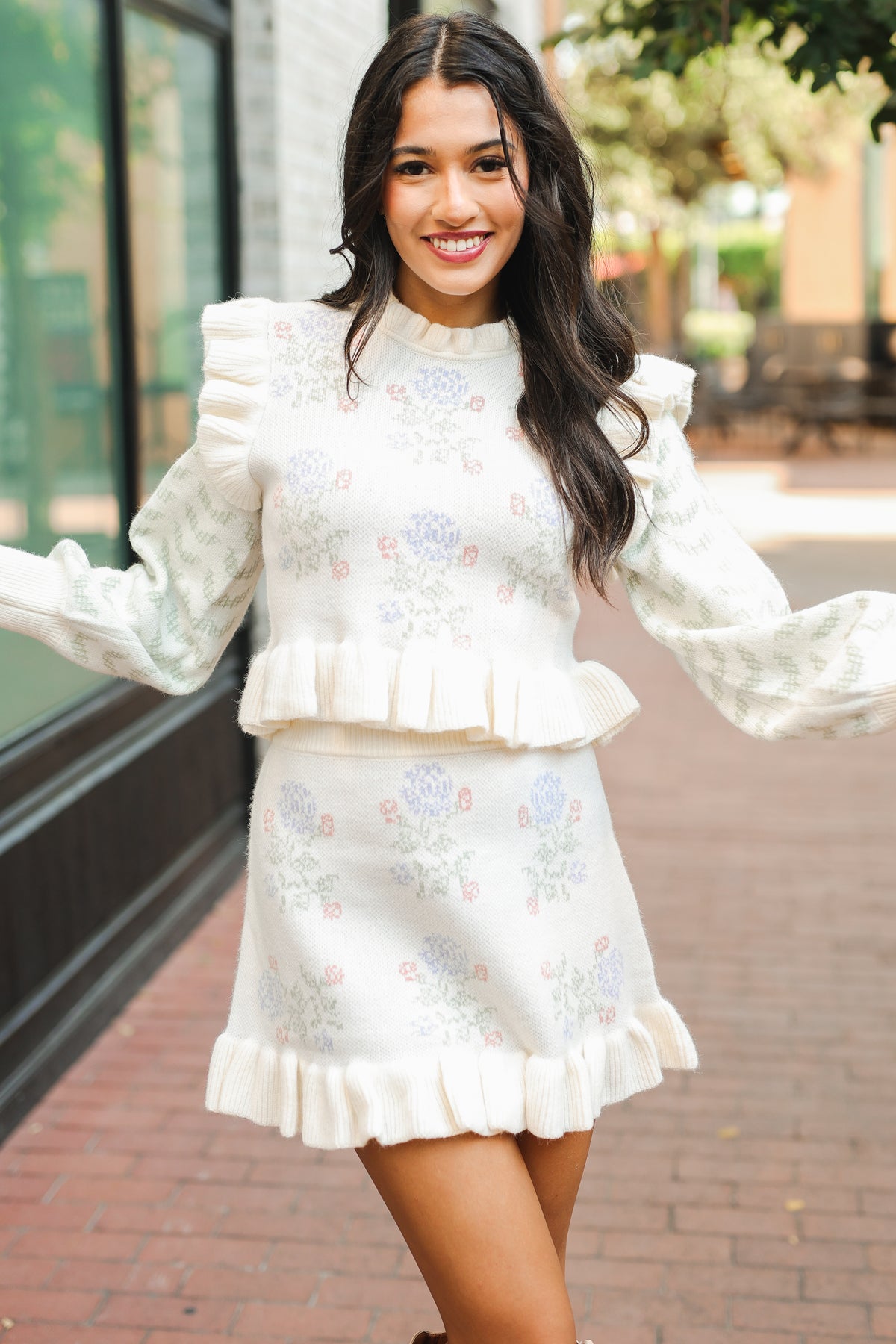 Woman wearing a white embroidered outfit with long sleeves and skirt on a blurred outdoor background
