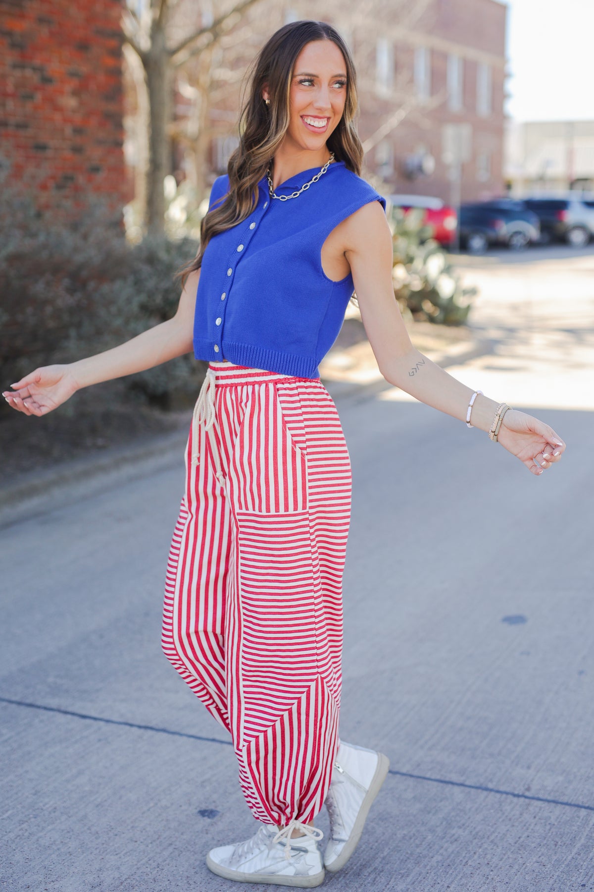 Woman wearing a blue top and red and white striped pants on a sidewalk.