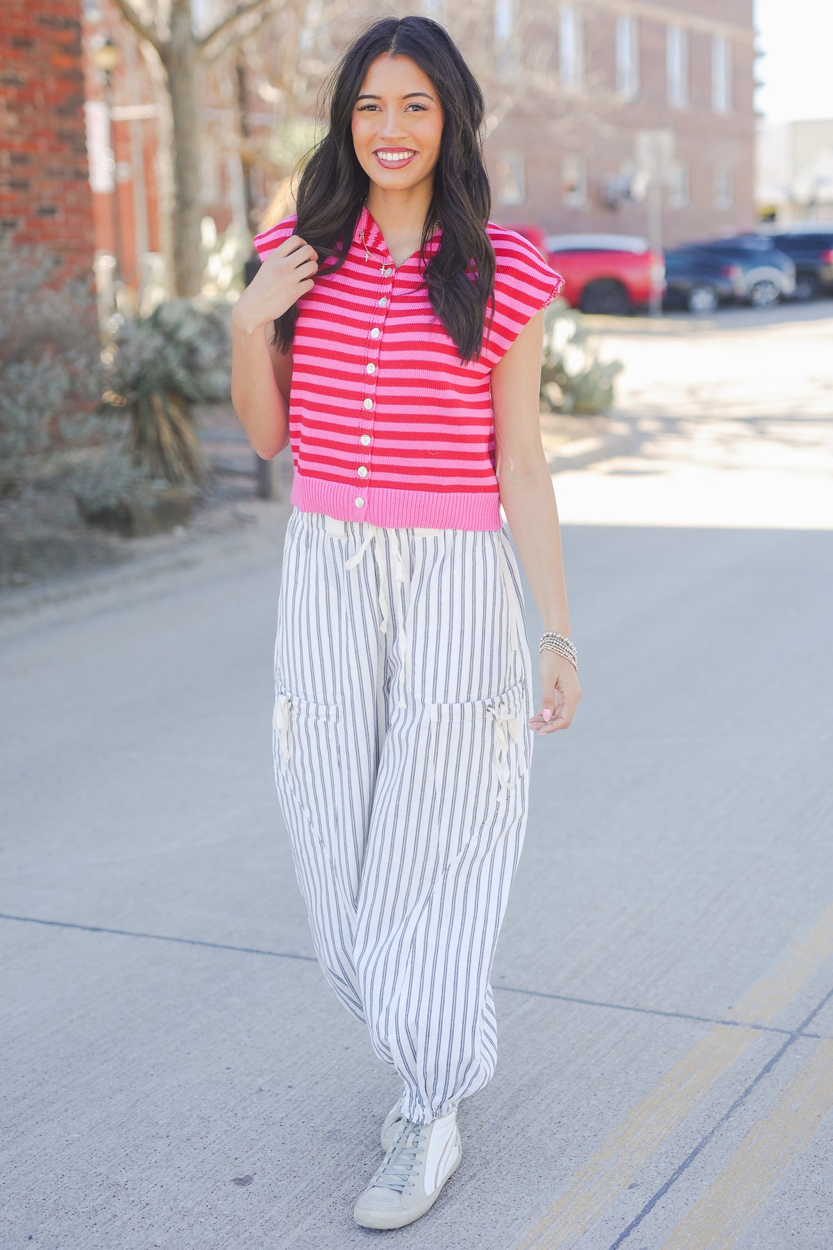 Woman wearing a red and white striped shirt with white pants on a street.