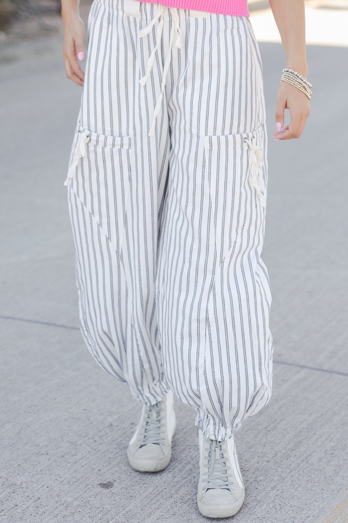 Person wearing white and gray striped pants on a gray pavement background