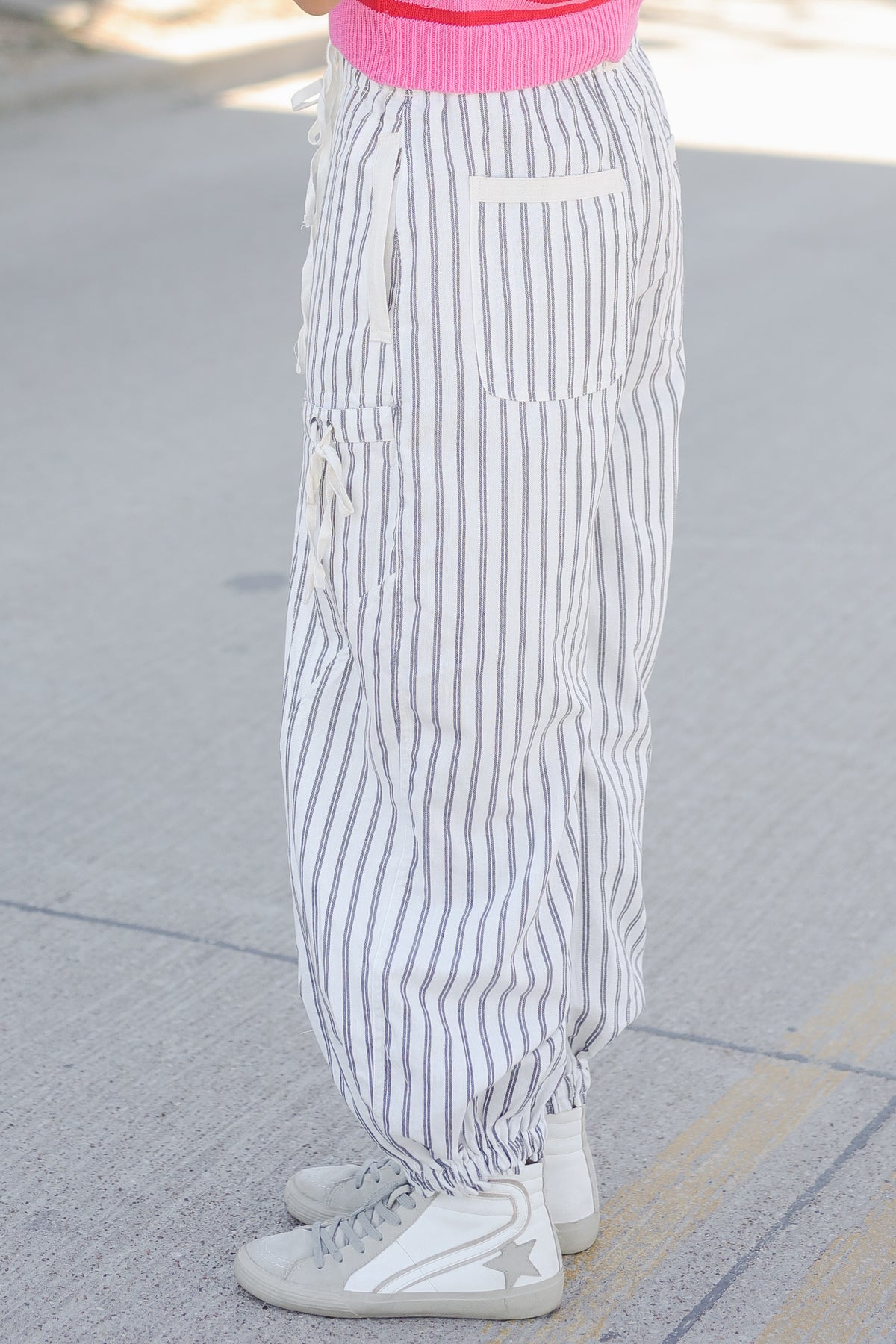 Person wearing white and gray striped pants on a sidewalk.