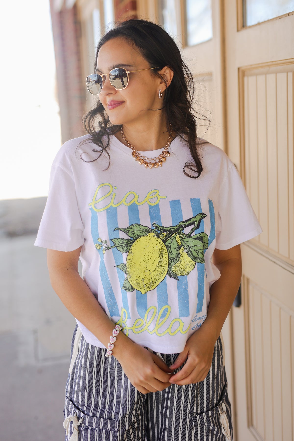 Woman wearing a white t-shirt with lemon design and text, standing indoors.