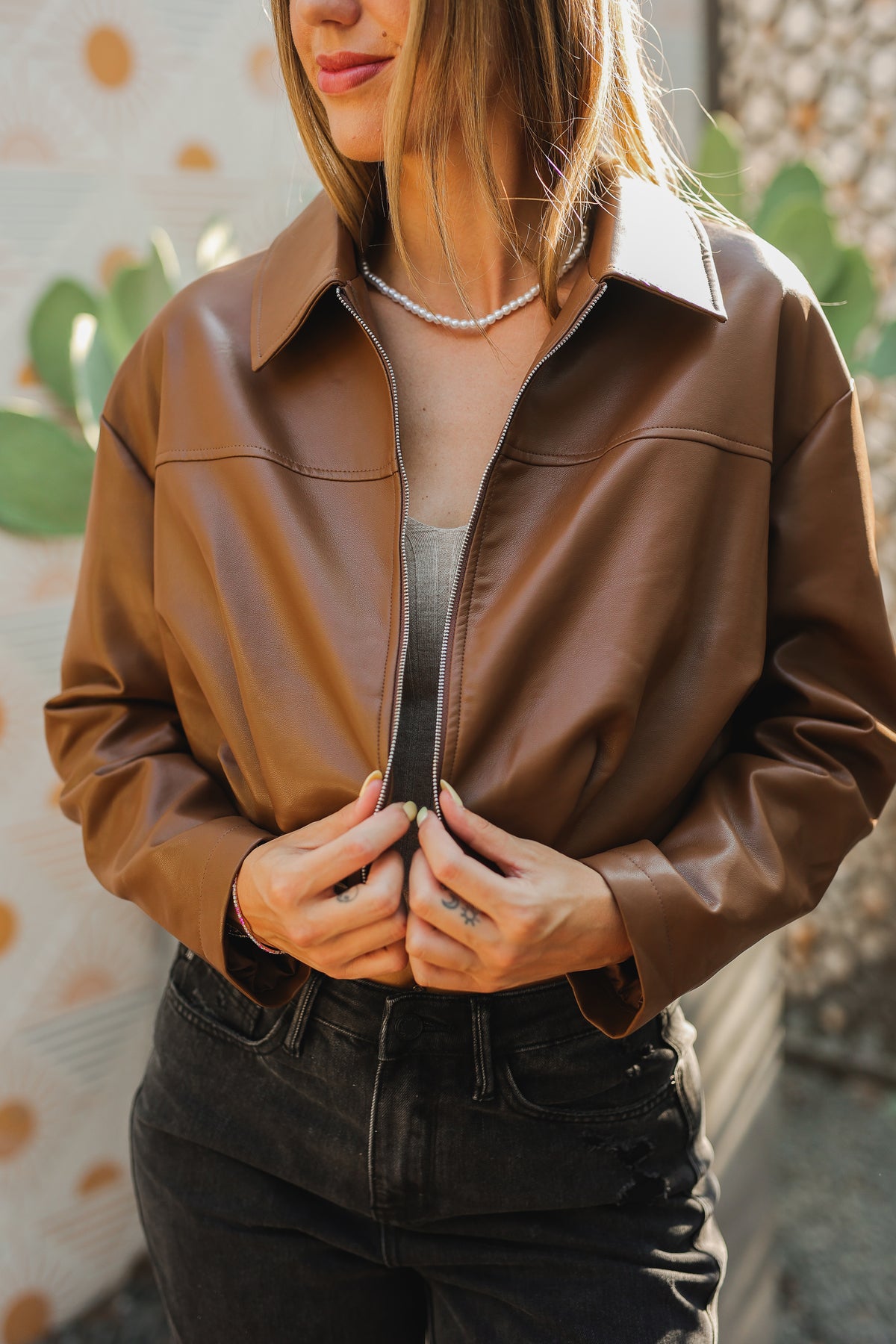 Person wearing a brown leather jacket with a blurred background
