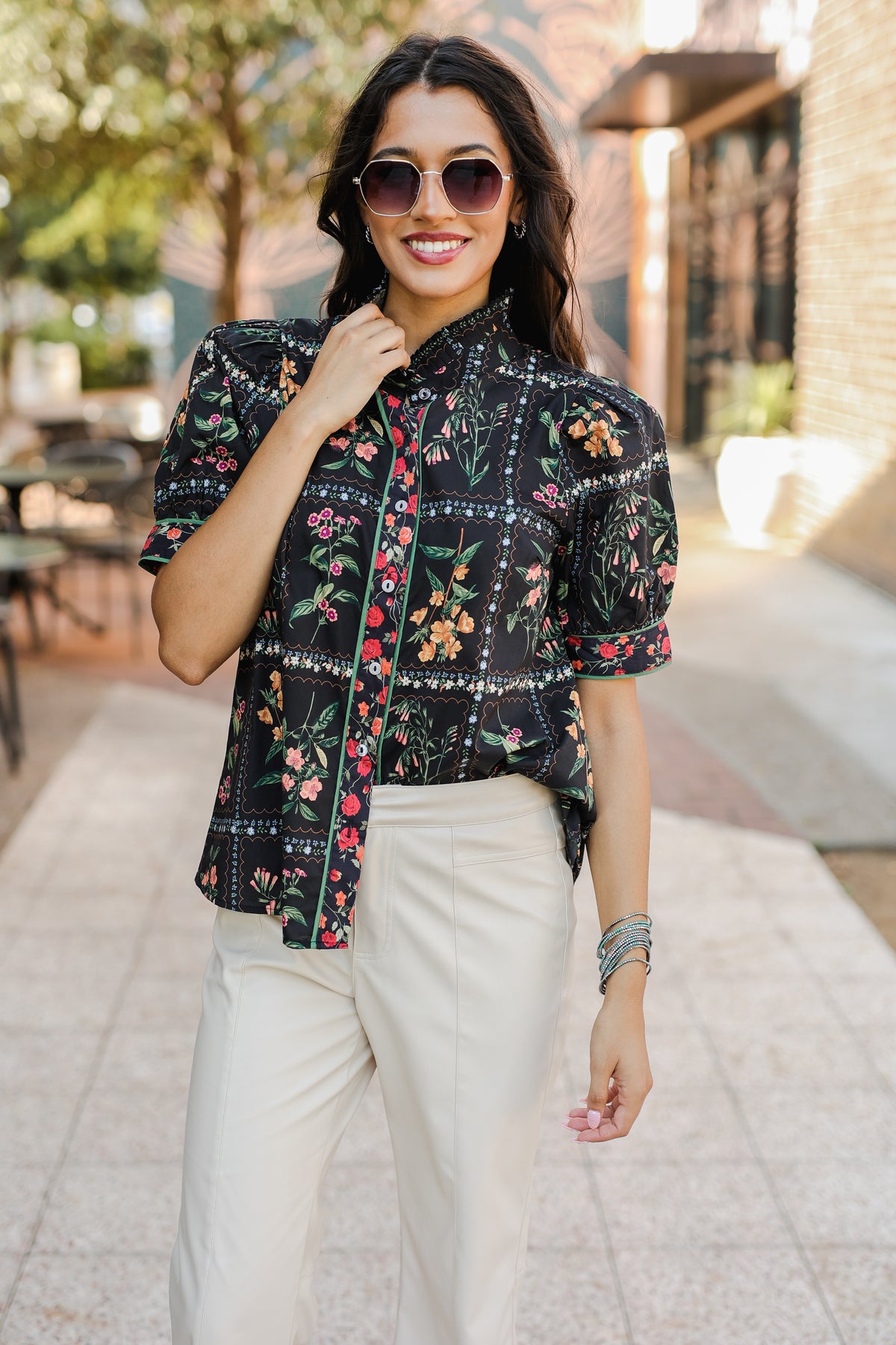 Woman wearing a floral blouse and sunglasses outdoors