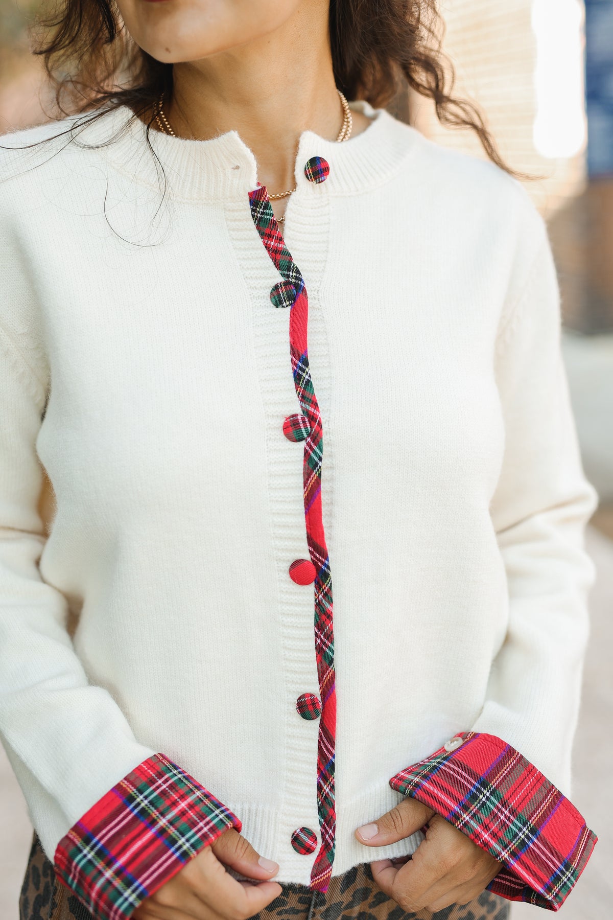 White cardigan with red and black plaid buttons and cuffs