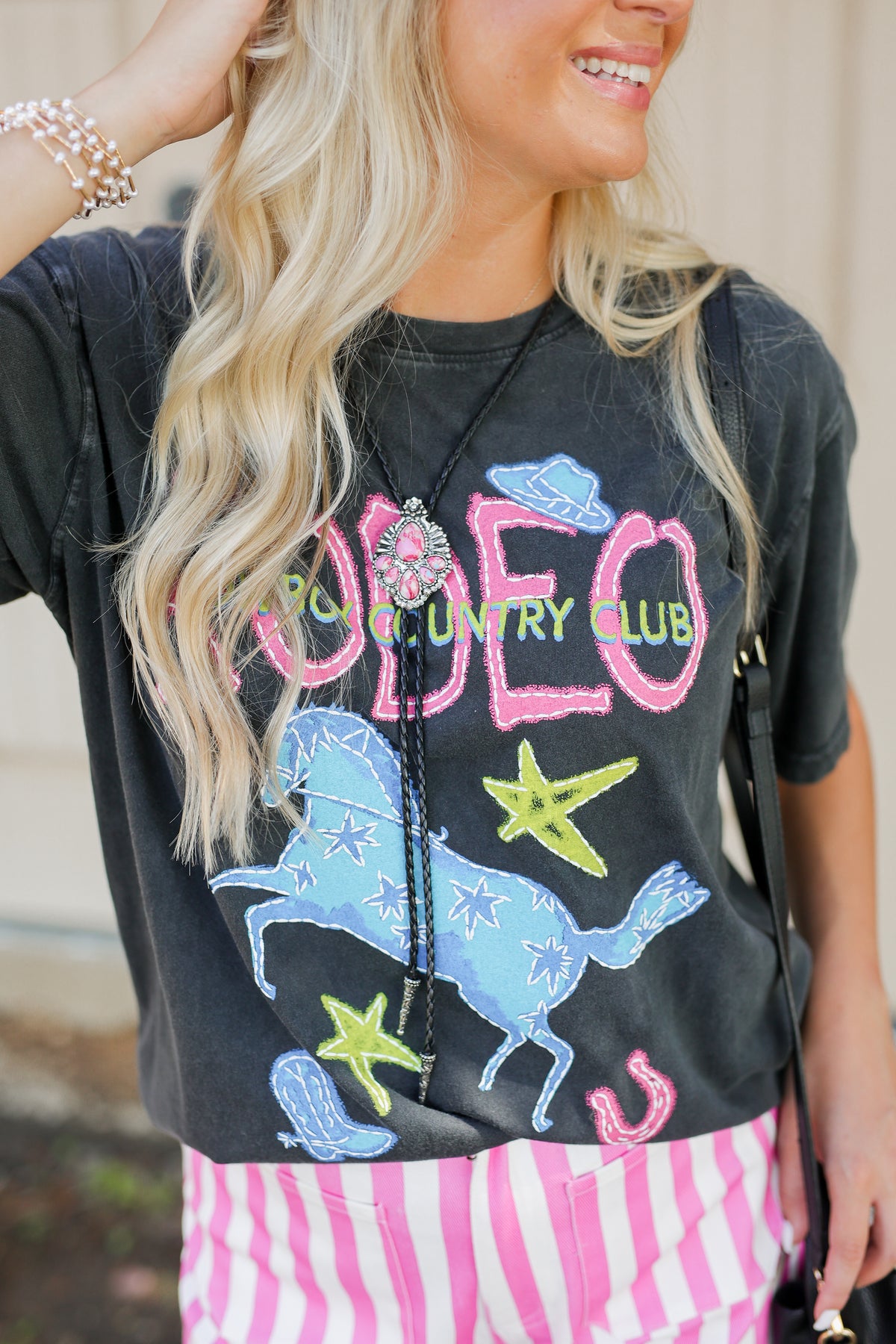 Person wearing a black t-shirt with colorful graphics and text, standing outdoors.