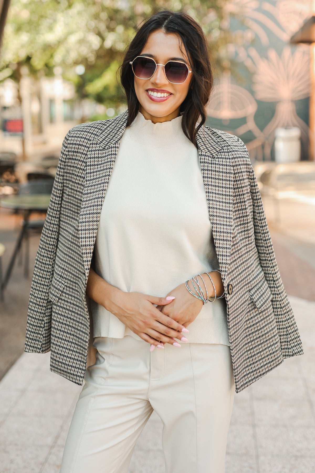 Woman wearing a plaid blazer over a white top and pants outdoors.