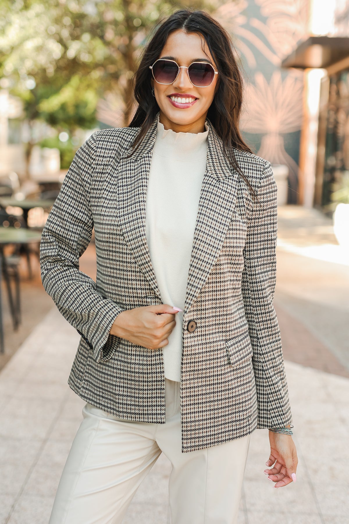 Woman wearing a checkered blazer and sunglasses outdoors