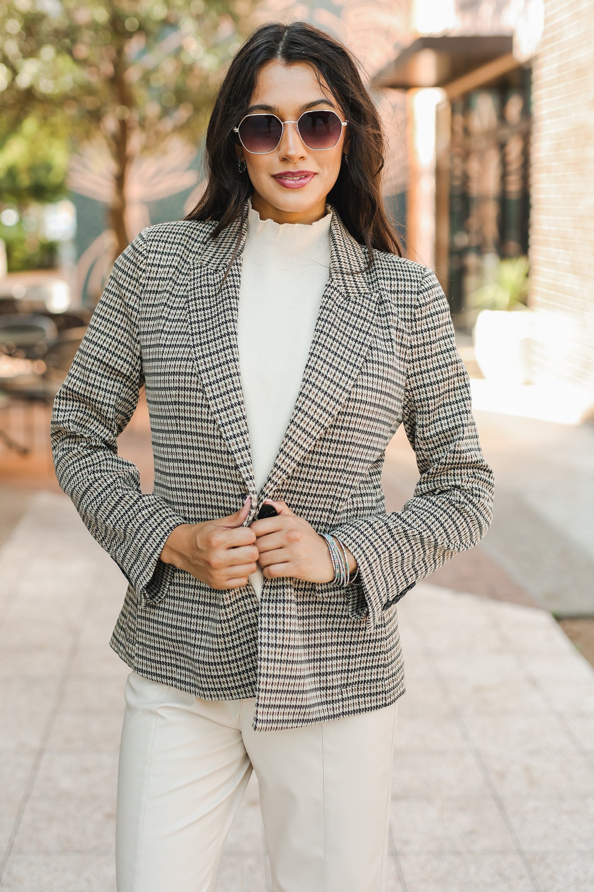 Woman wearing a checkered blazer and sunglasses outdoors