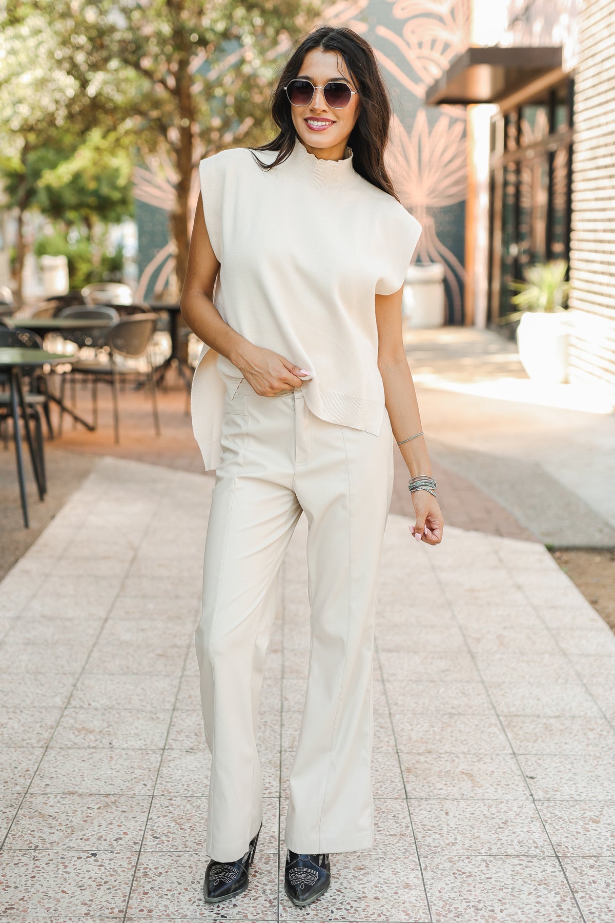 Woman in a white outfit standing outdoors on a sunny day.