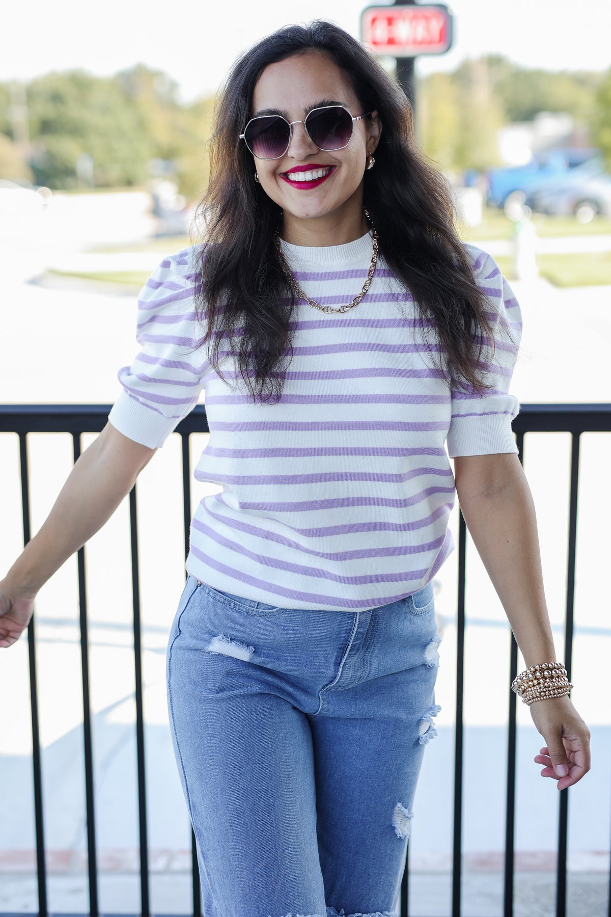 Woman wearing a striped shirt and jeans standing outdoors.