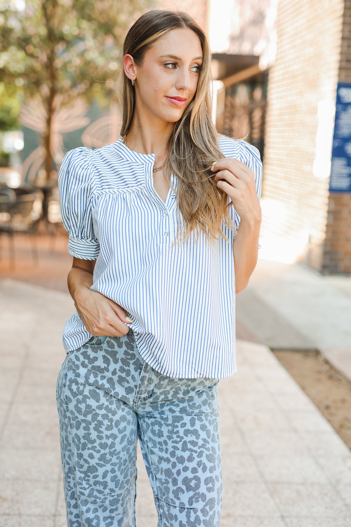 Woman wearing a blue and white striped shirt and leopard print pants outdoors.