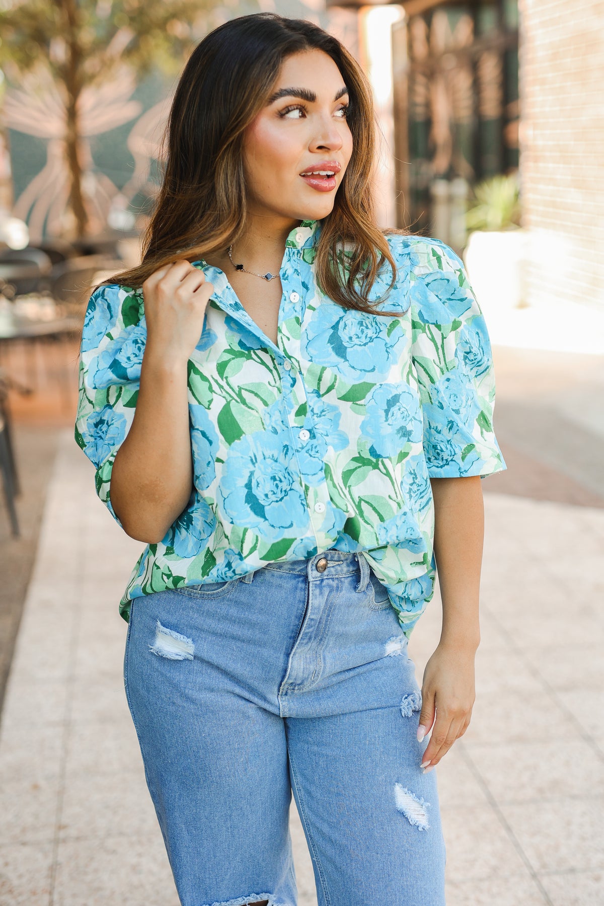 Woman wearing a blue floral blouse and jeans outdoors