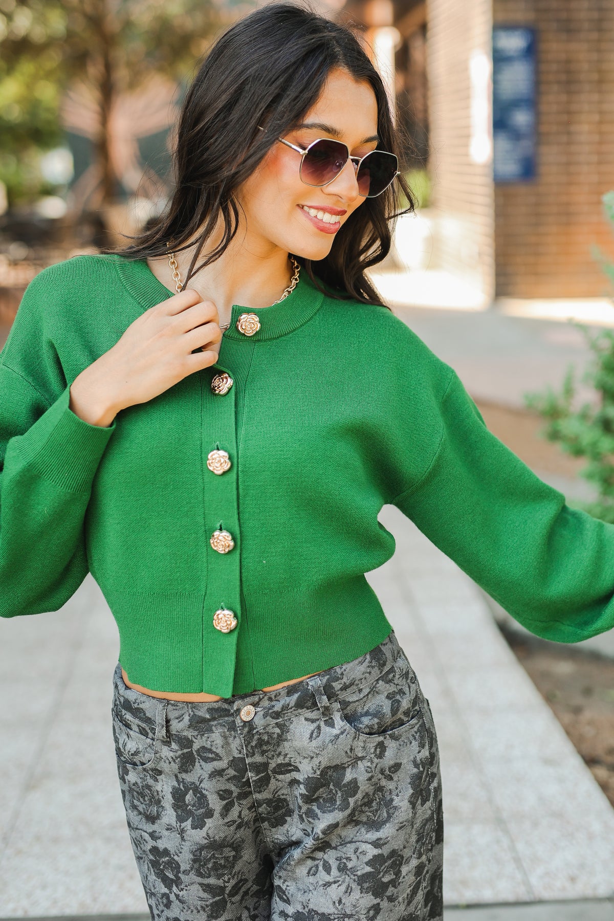 Woman wearing a green cardigan with floral pants outdoors