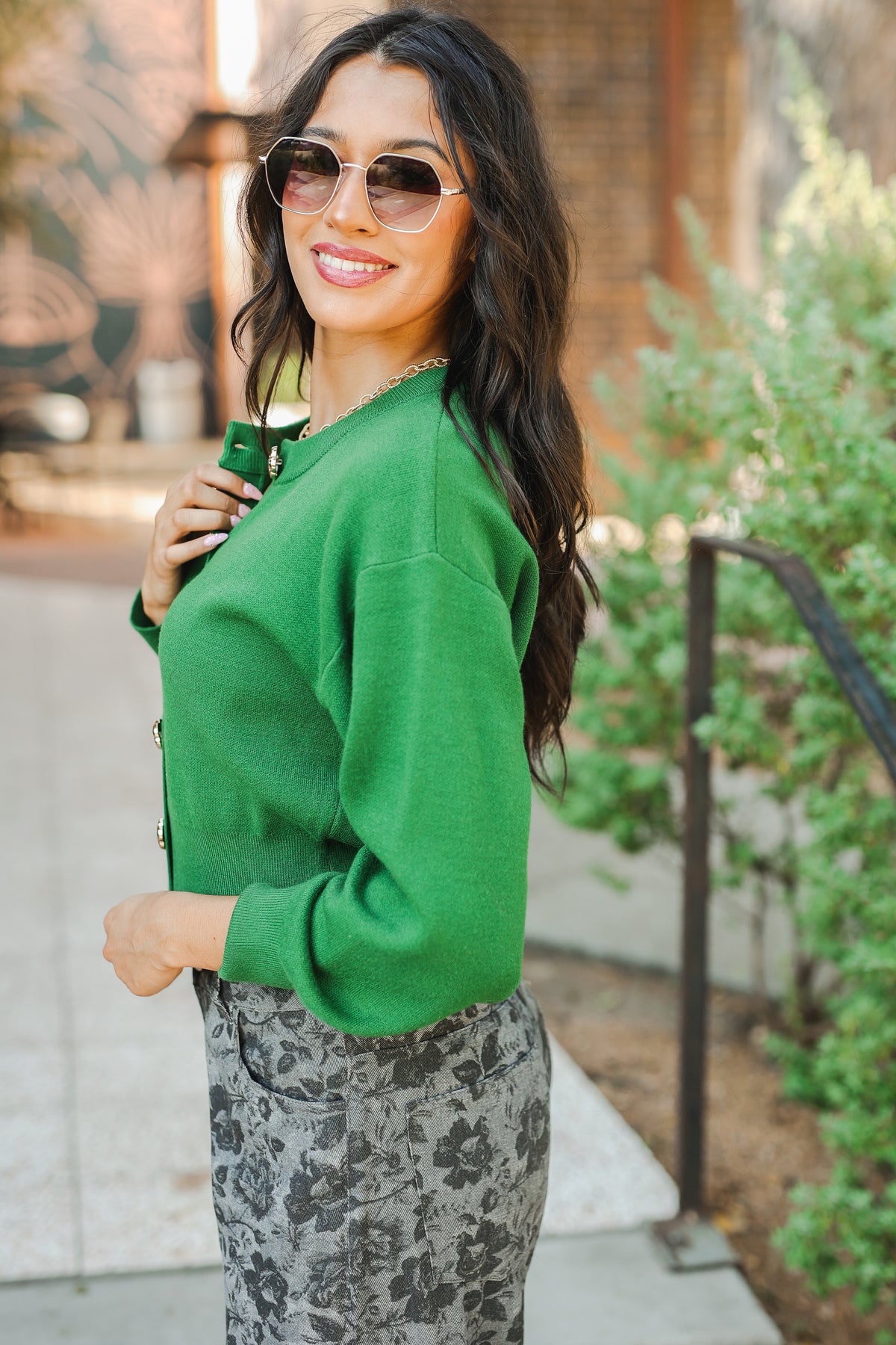 Woman wearing a green sweater and sunglasses outdoors