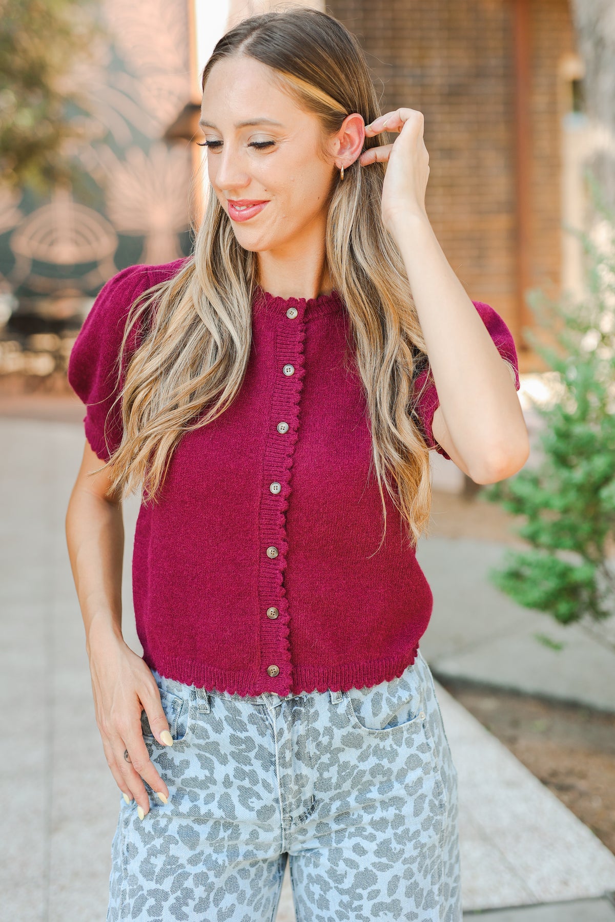 Woman wearing a maroon cardigan with a blurred outdoor background