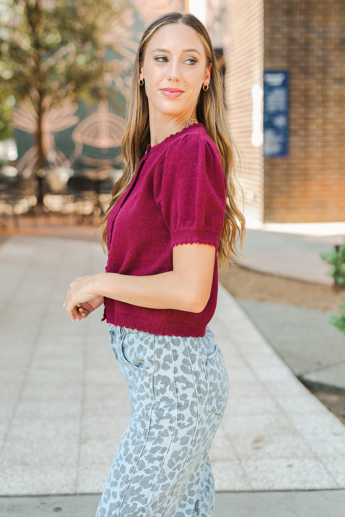Woman wearing a maroon sweater and patterned pants outdoors.