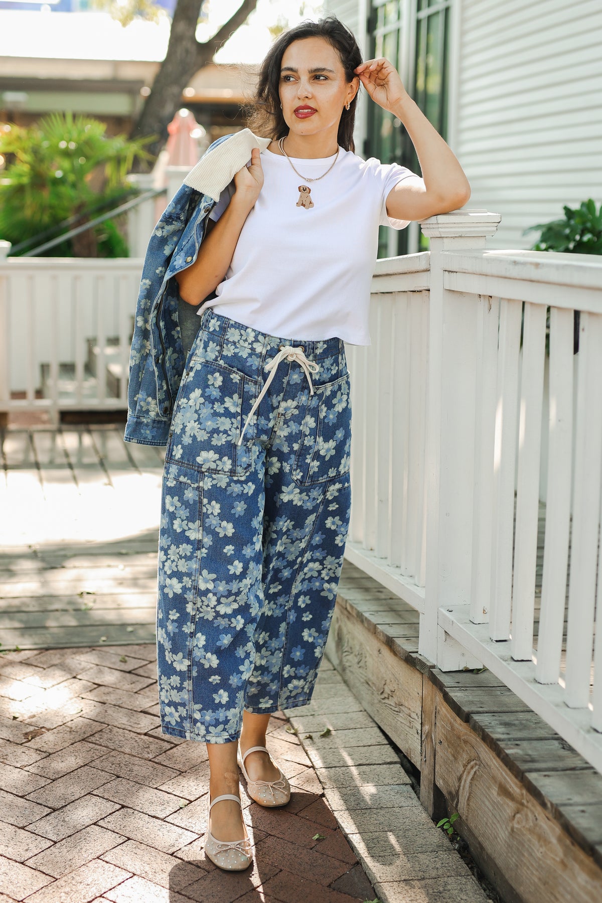 Woman wearing a white t-shirt and blue floral pants on a porch.