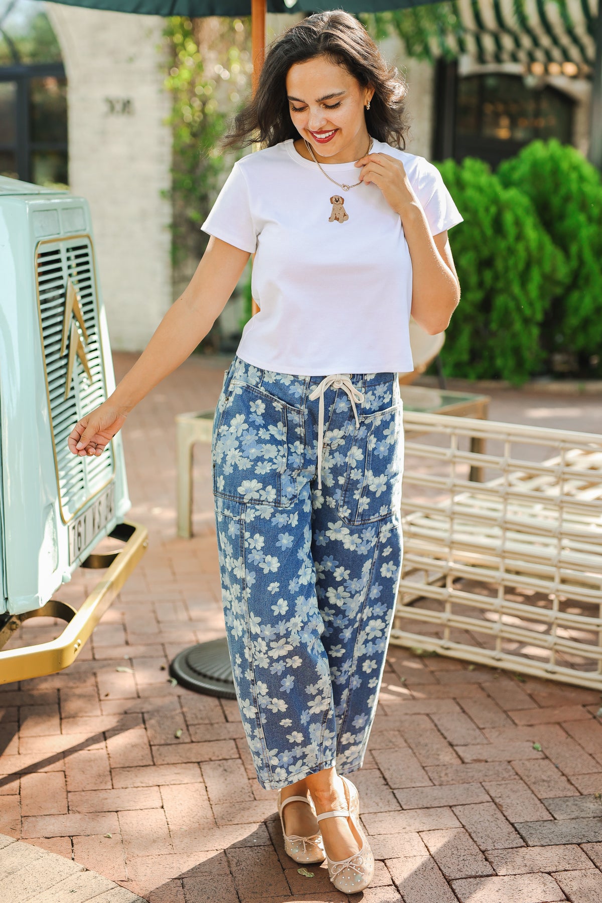 Woman wearing a white t-shirt and blue floral pants outdoors.