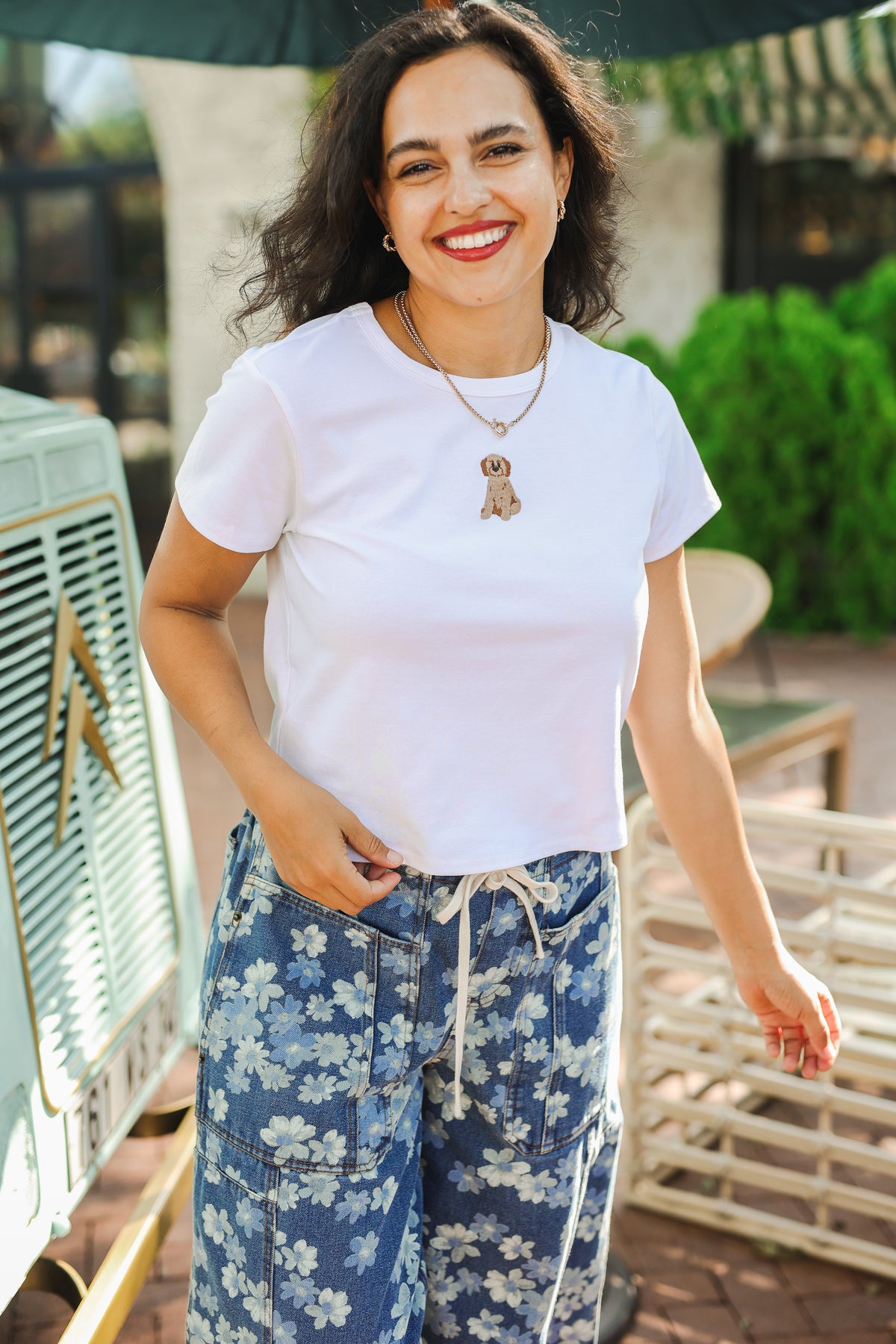 Woman wearing a white t-shirt and floral pants outdoors