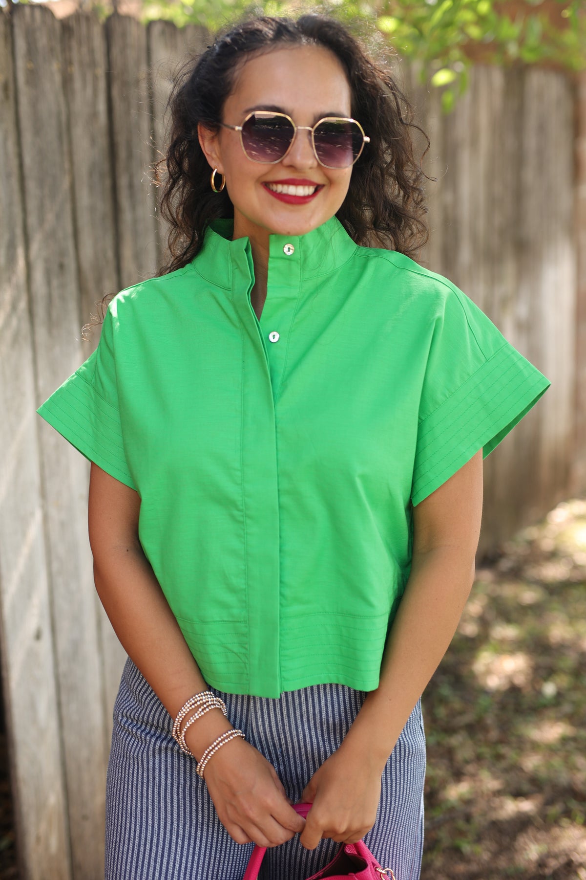 Woman wearing a green top and sunglasses outdoors