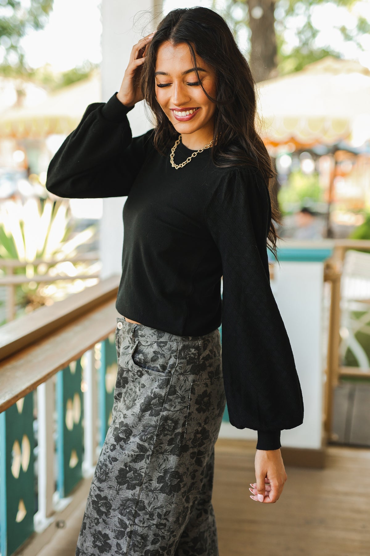 Woman wearing a black top and patterned pants outdoors