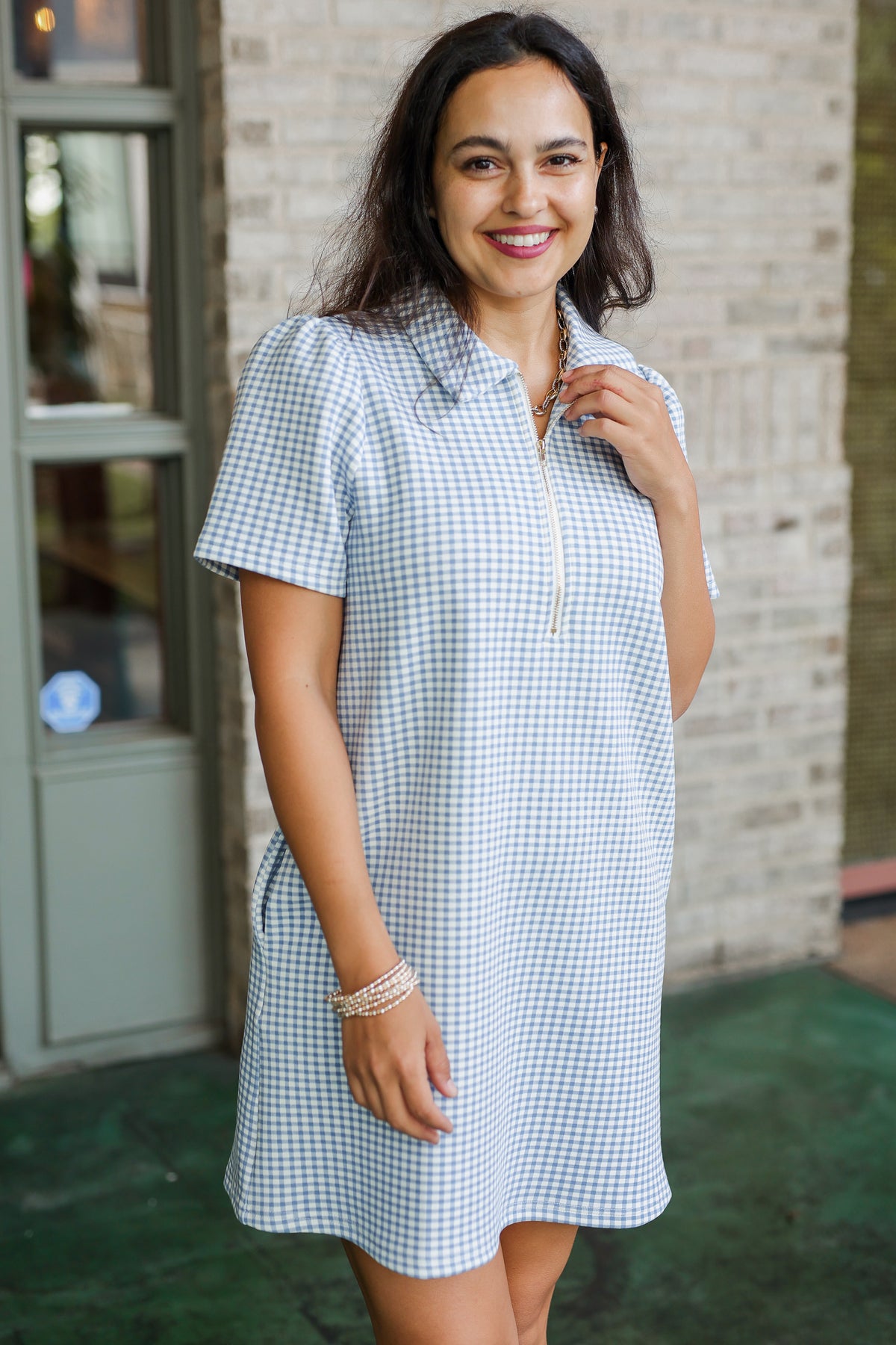Woman wearing a checkered dress standing in front of a building.