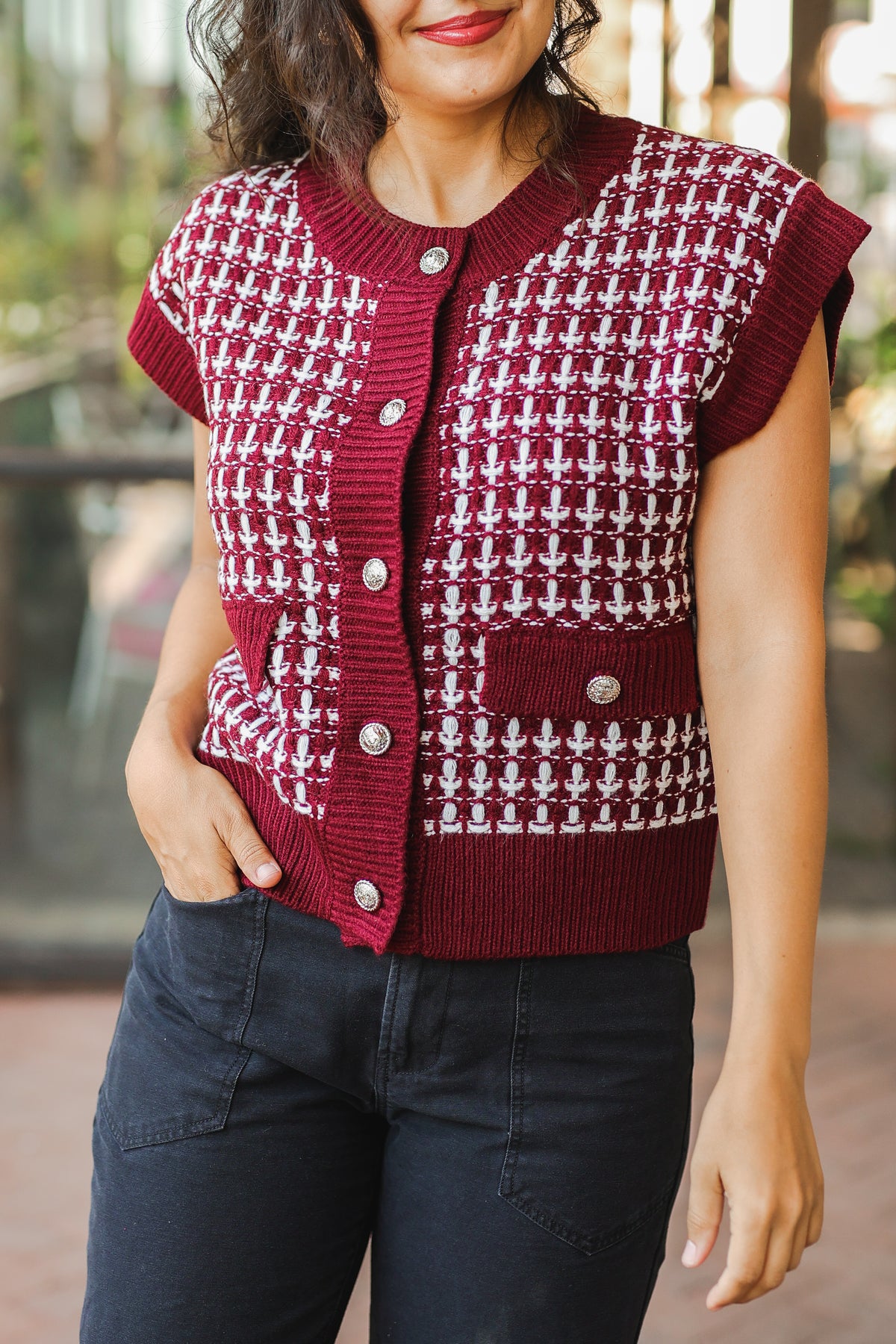 Woman wearing a red and white patterned vest with a blurred background