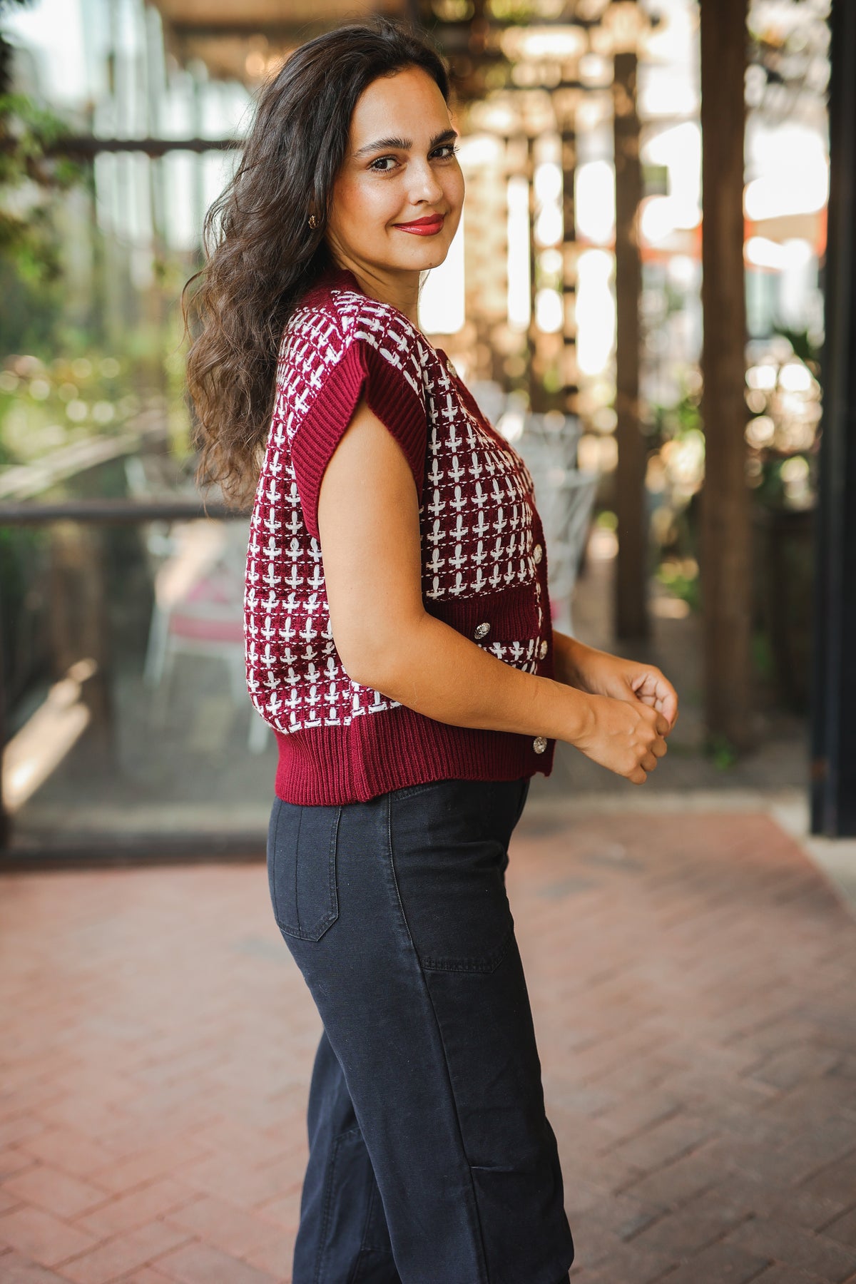 Woman wearing a patterned vest and dark pants outdoors