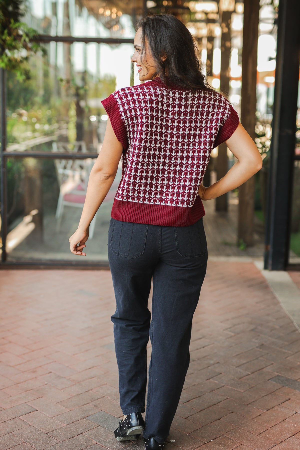 Woman wearing a patterned short-sleeve top and dark pants walking outdoors.