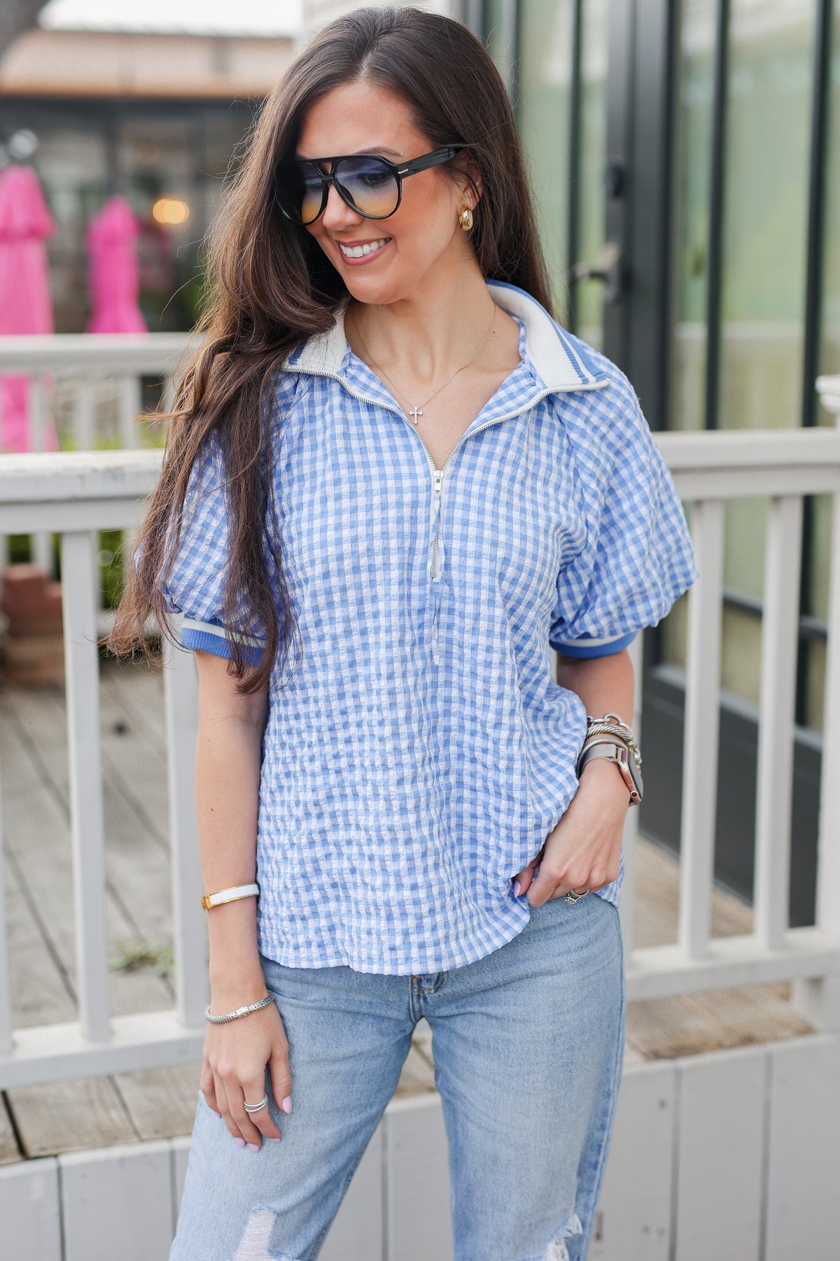Woman wearing a blue checkered shirt and jeans outdoors.