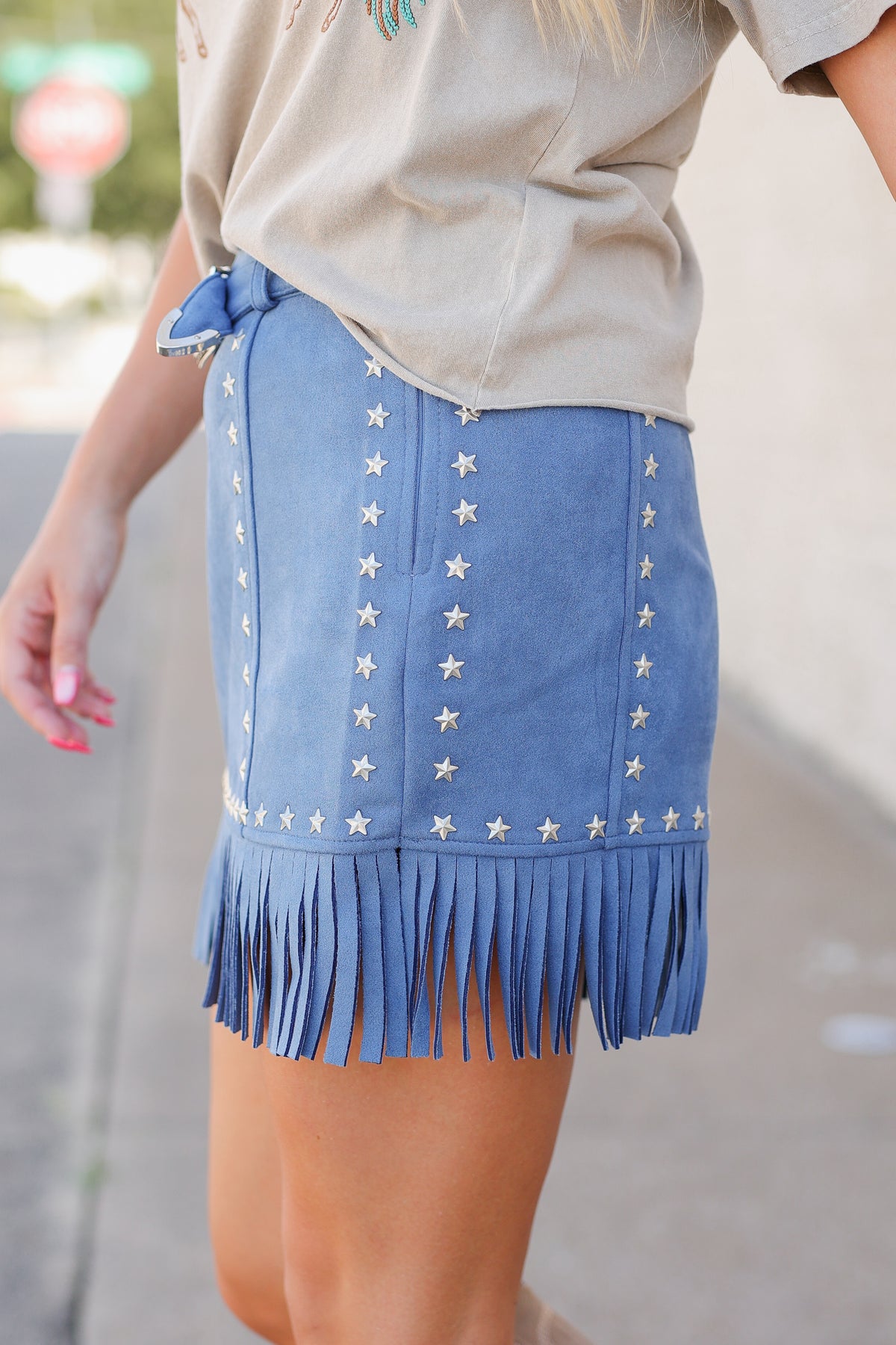 Close up of a blue fringe skirt with star studs.