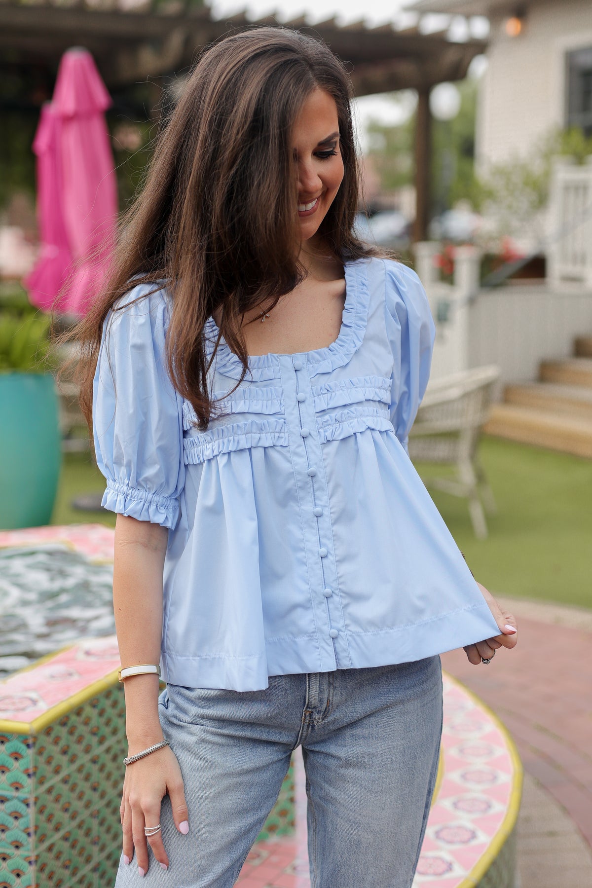 Woman wearing a light blue blouse and jeans outdoors