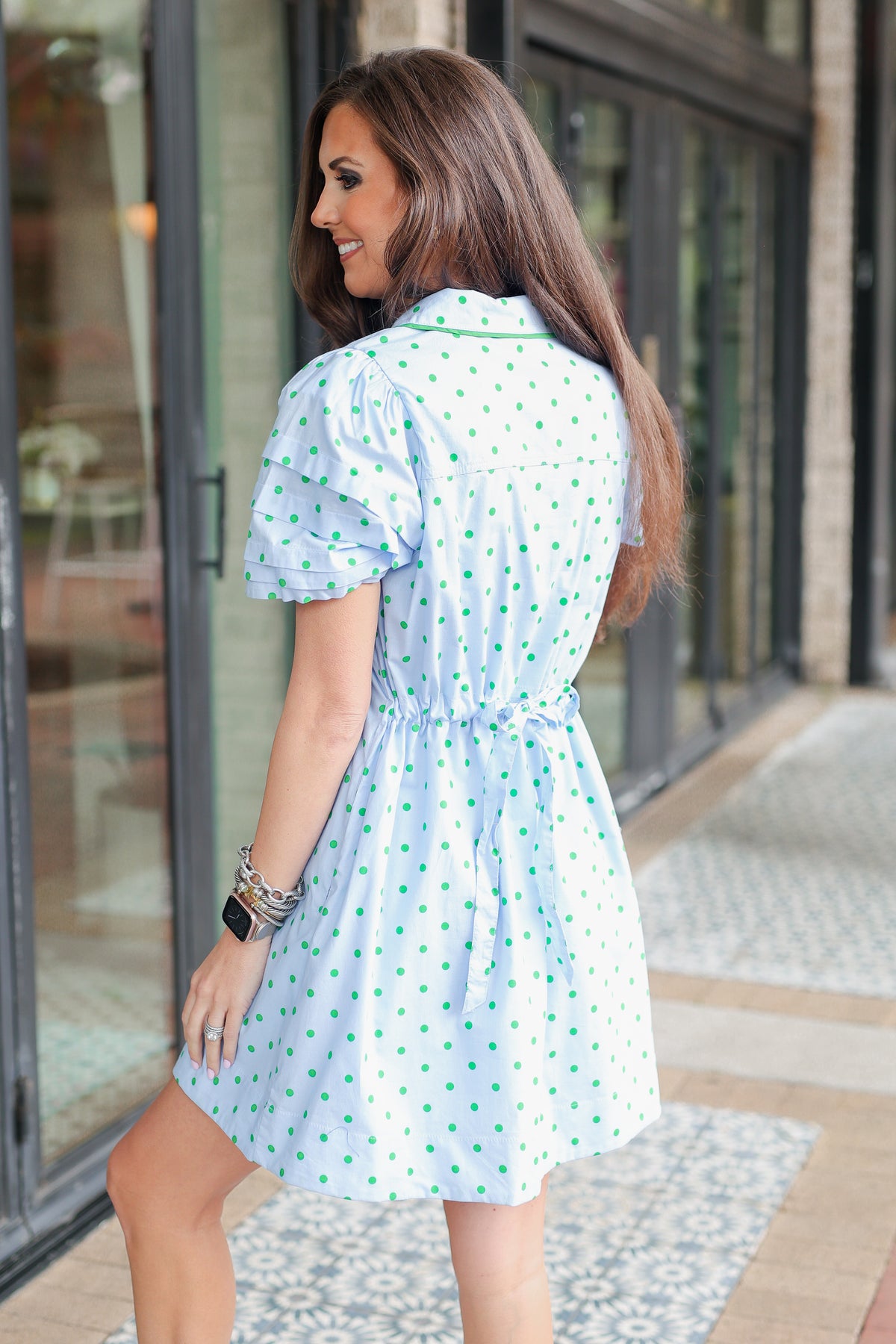 Woman wearing a light blue dress with a pattern, standing outdoors.