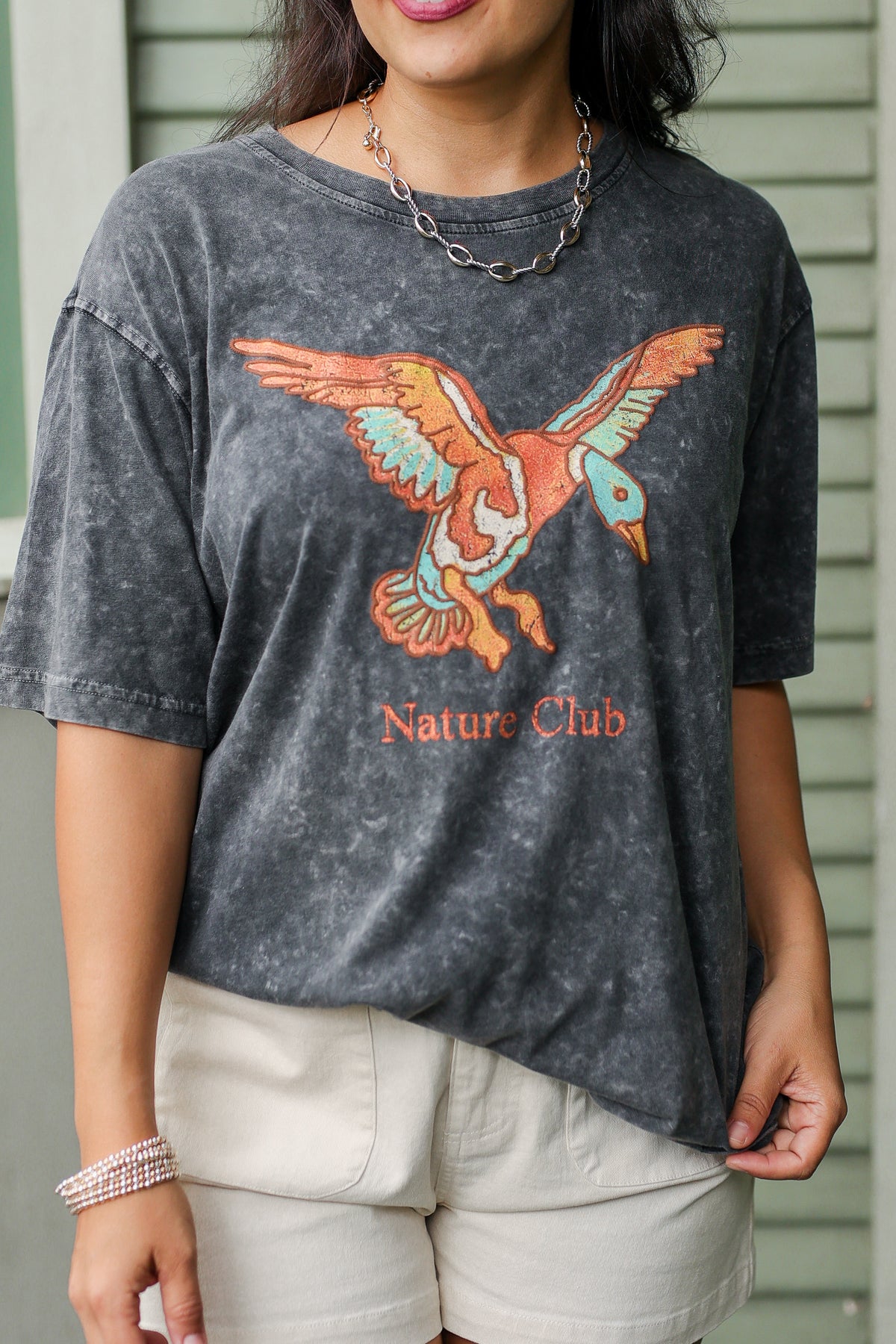 Person wearing a gray t-shirt with a bird graphic and 'Nature Club' text.