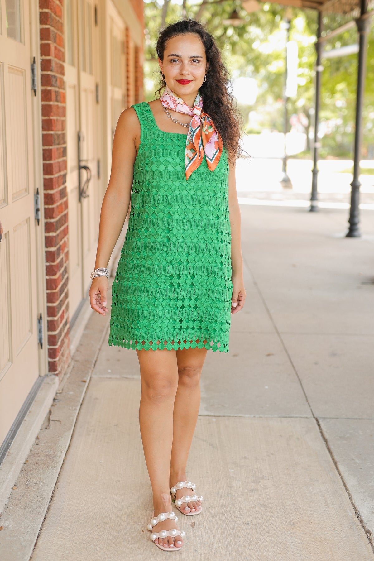 Woman wearing a green dress with a colorful scarf on a sidewalk