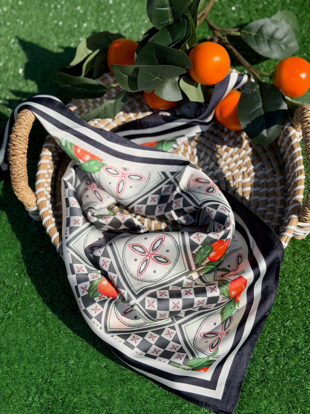 Patterned fabric with geometric and floral designs on a green surface with oranges and leaves.