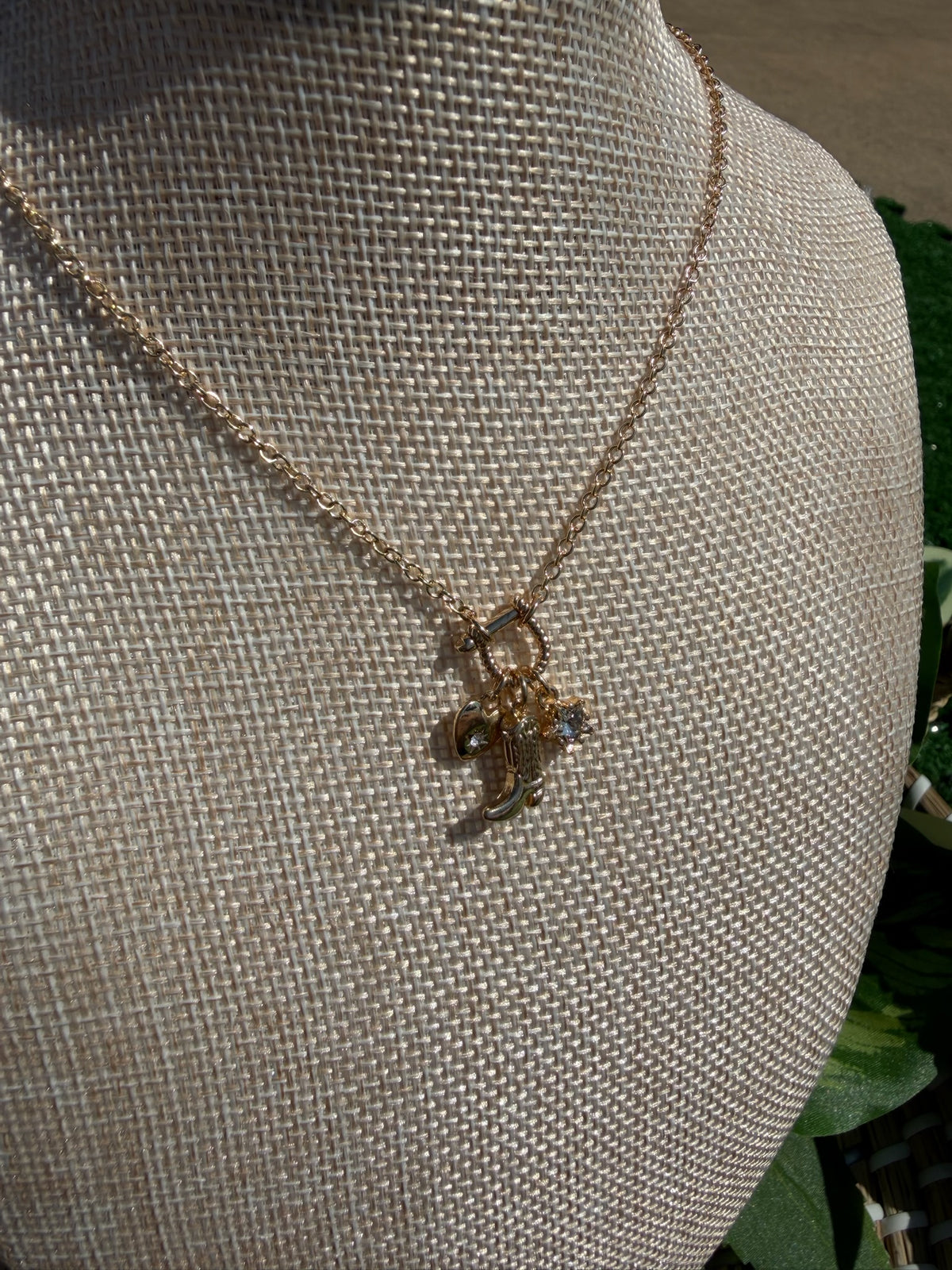 Gold necklace with a pendant on a mannequin bust.