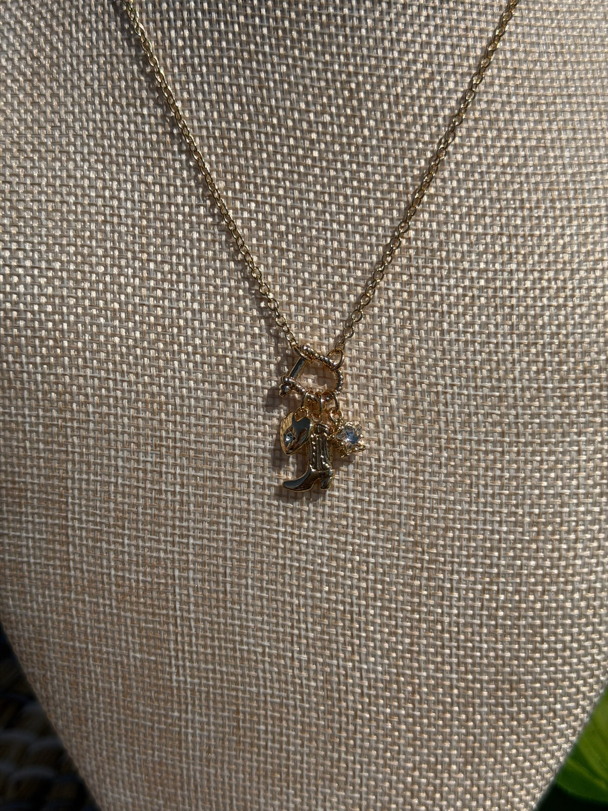 Gold necklace with a small pendant on a textured beige surface