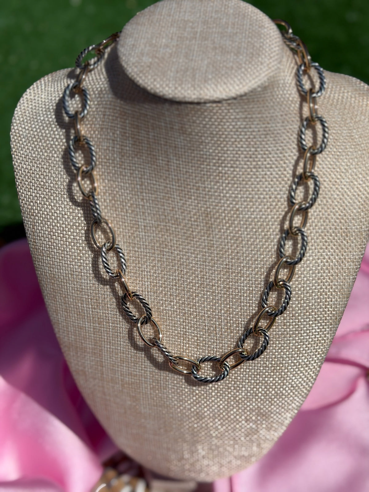 Necklace on a mannequin bust with a pink fabric background