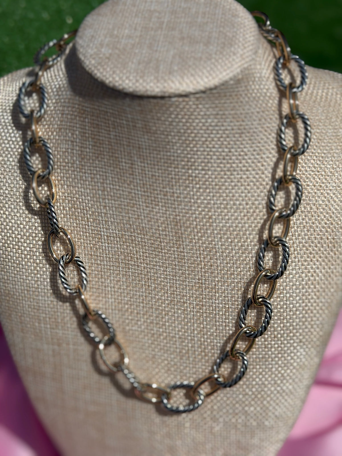 Chain necklace on a mannequin bust with a blurred green background