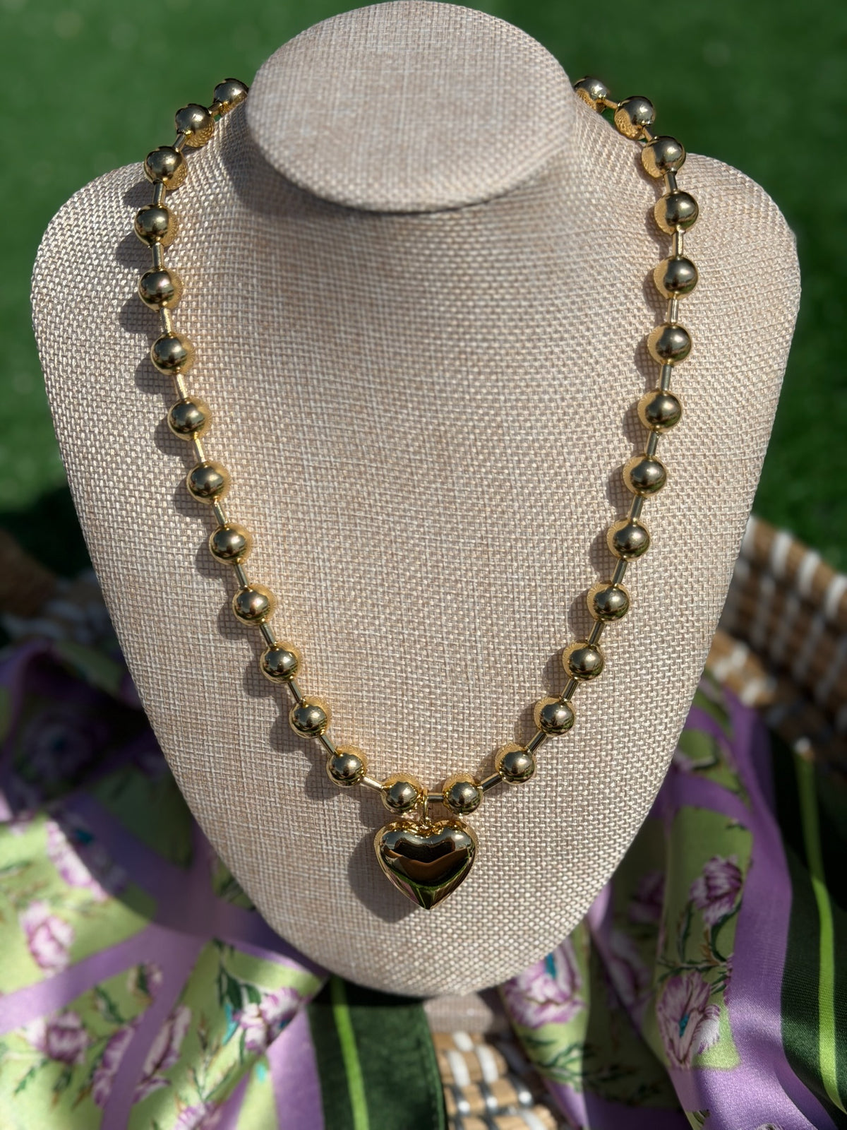 Necklace with heart pendant on a mannequin bust against a green background