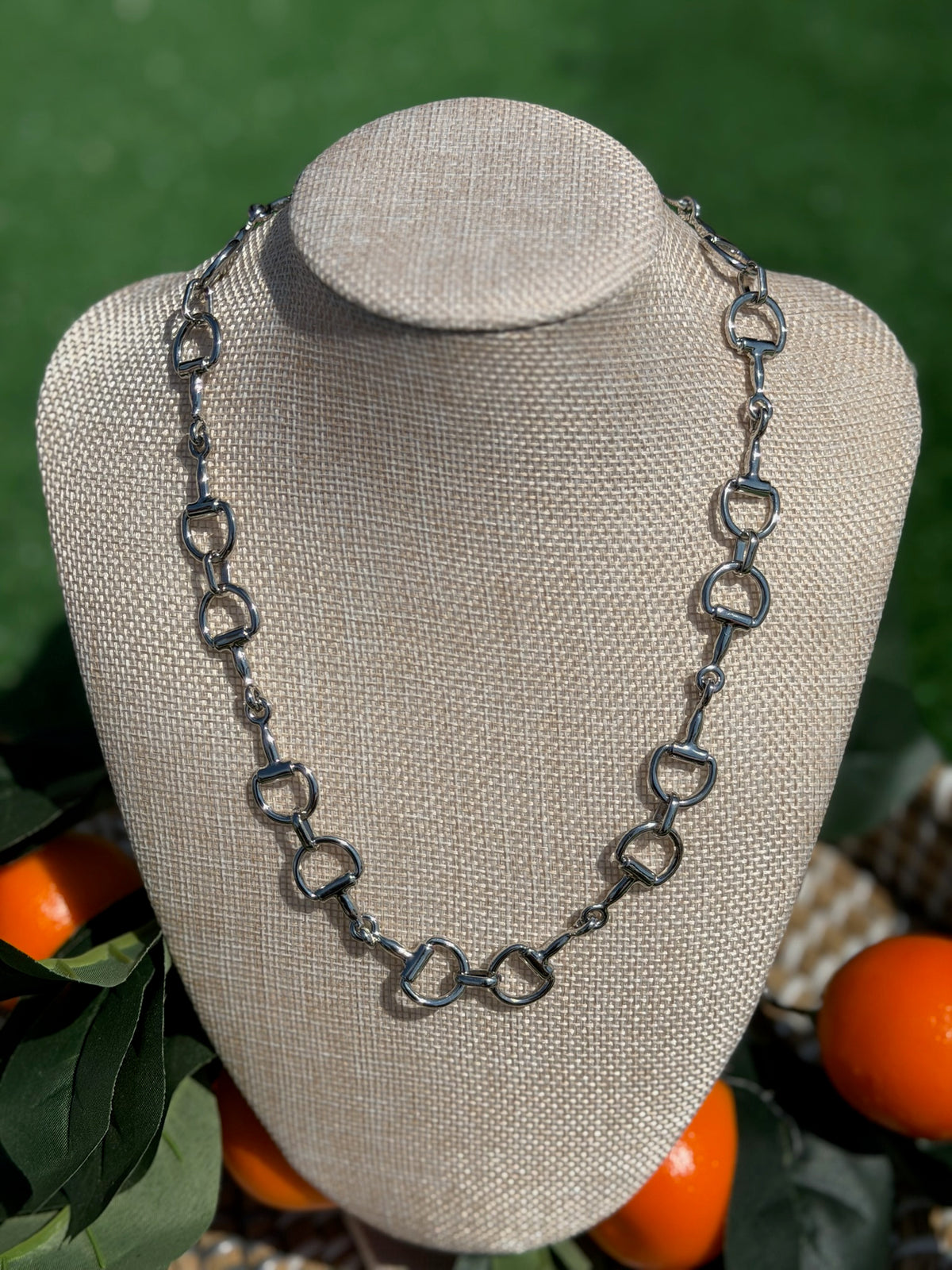 Silver chain necklace on a gray bust with a green background