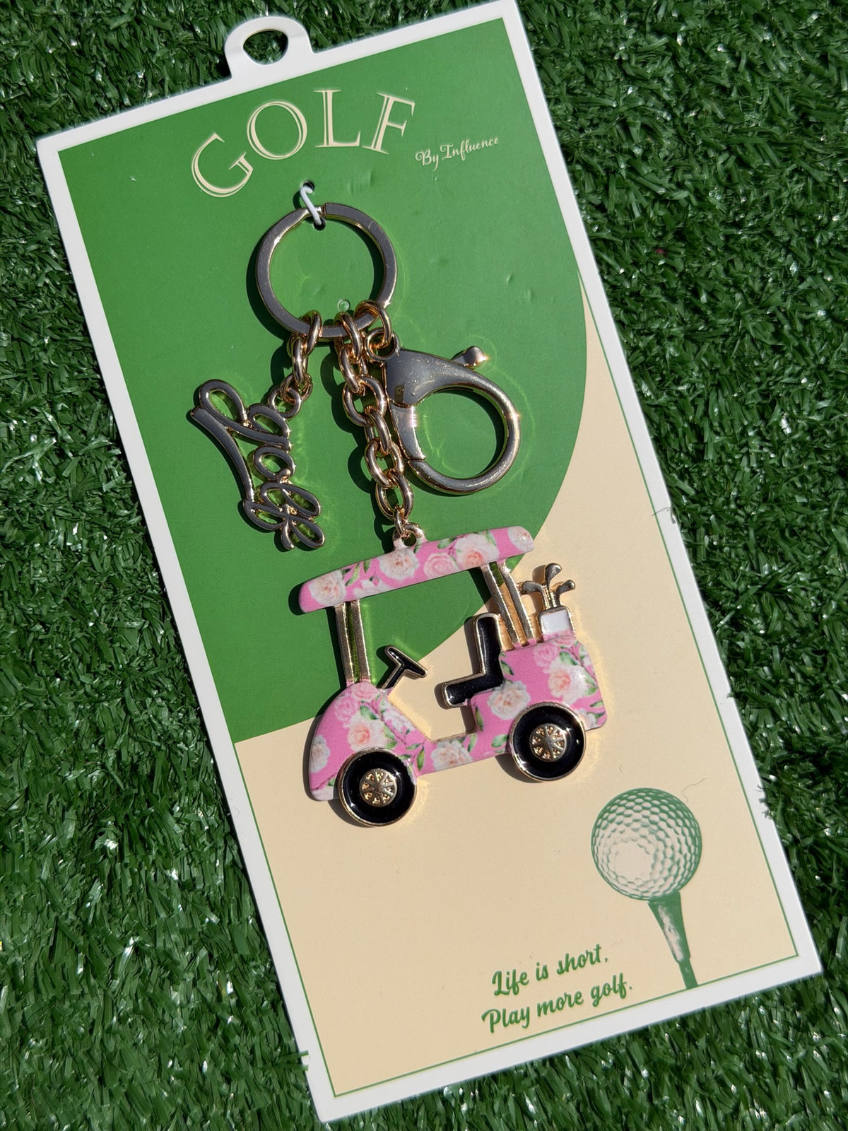 Golf-themed keychain with pink golf cart design on a green and beige card.