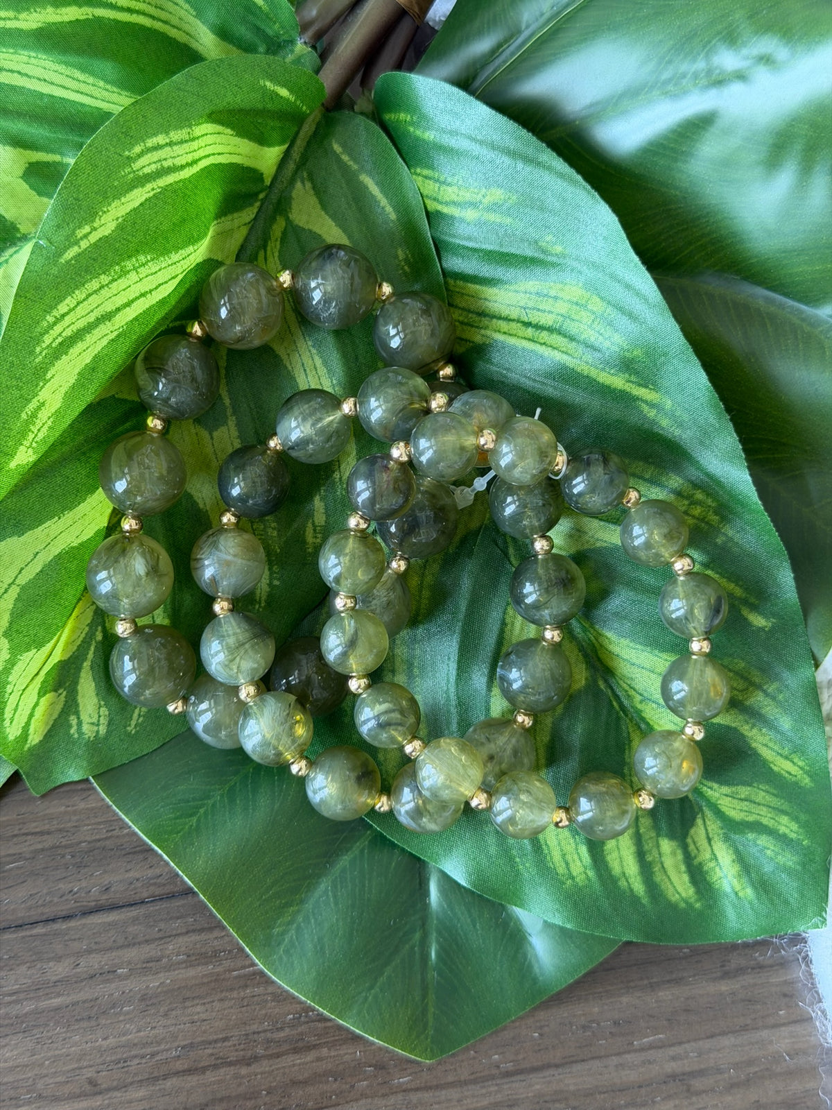 Green beaded necklace on a large green leaf